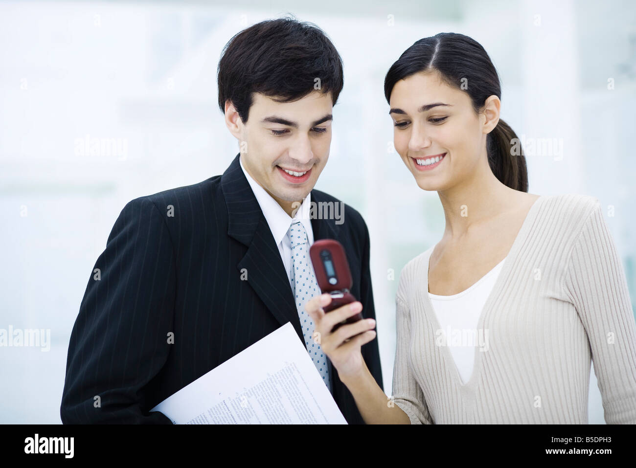 Colleagues looking at cell phone together, smiling Stock Photo