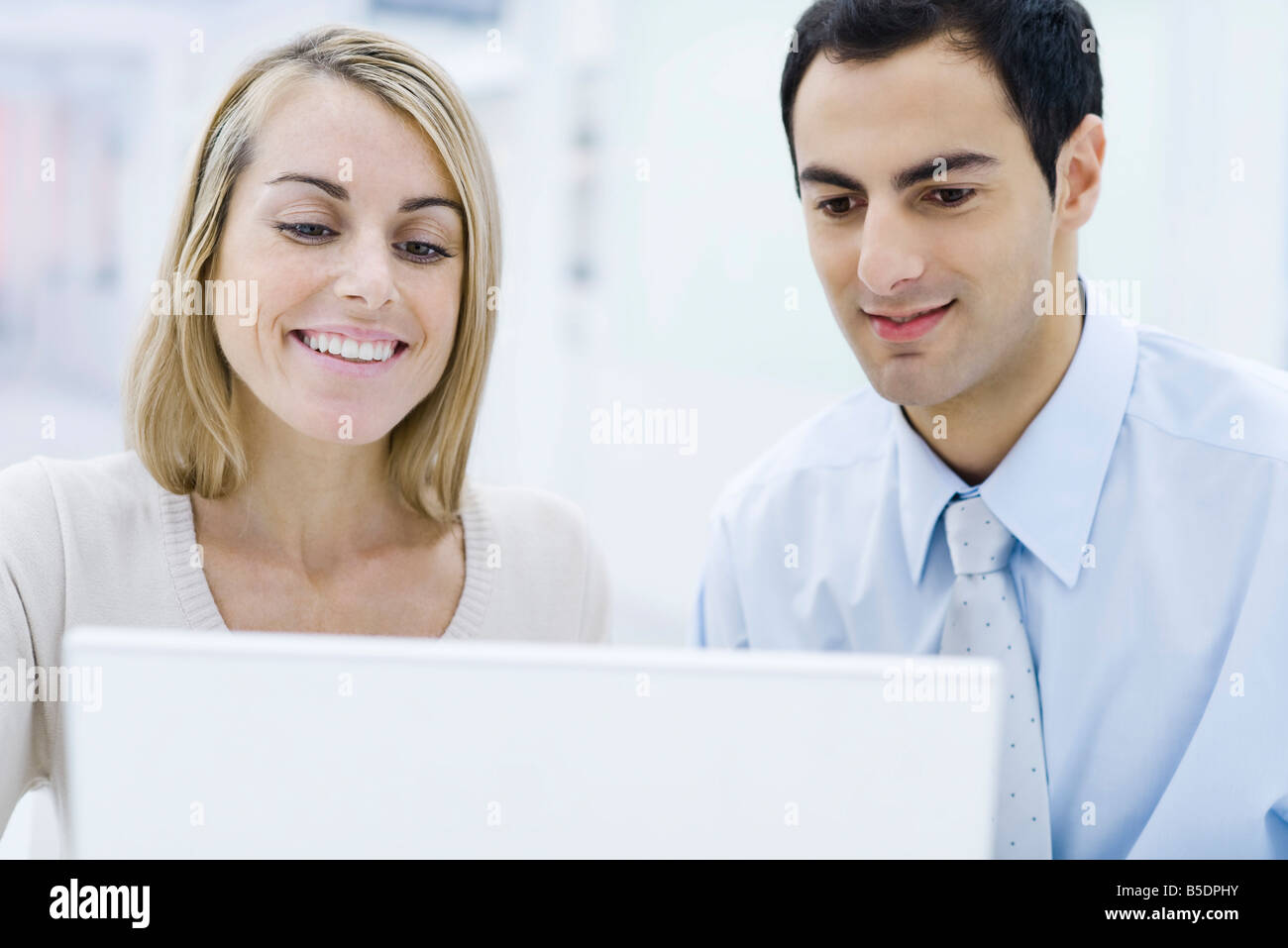 Two professionals looking at laptop computer together, smiling Stock Photo