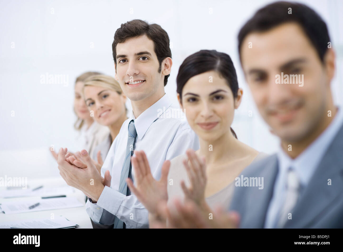 Group of professionals clapping, smiling at camera Stock Photo