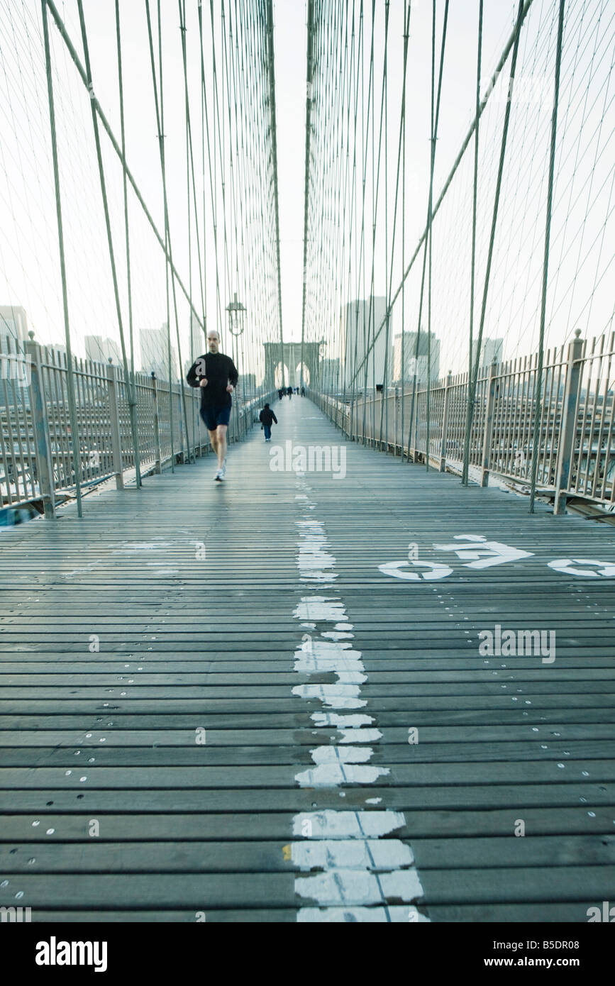 Jogger running across pedestrian walkway of Brooklyn Bridge in New York ...