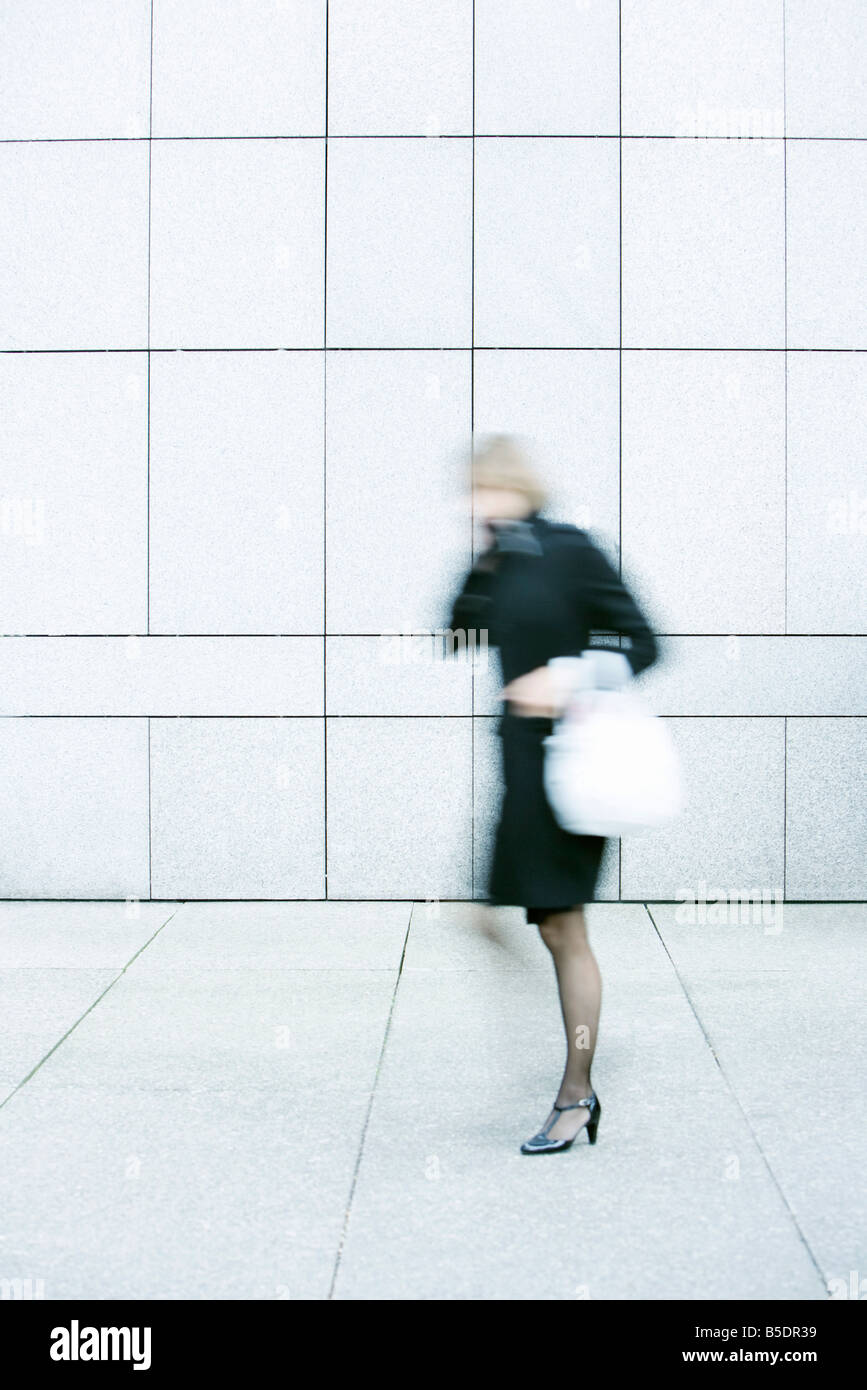 Businesswoman talking on phone while walking down sidewalk Stock Photo