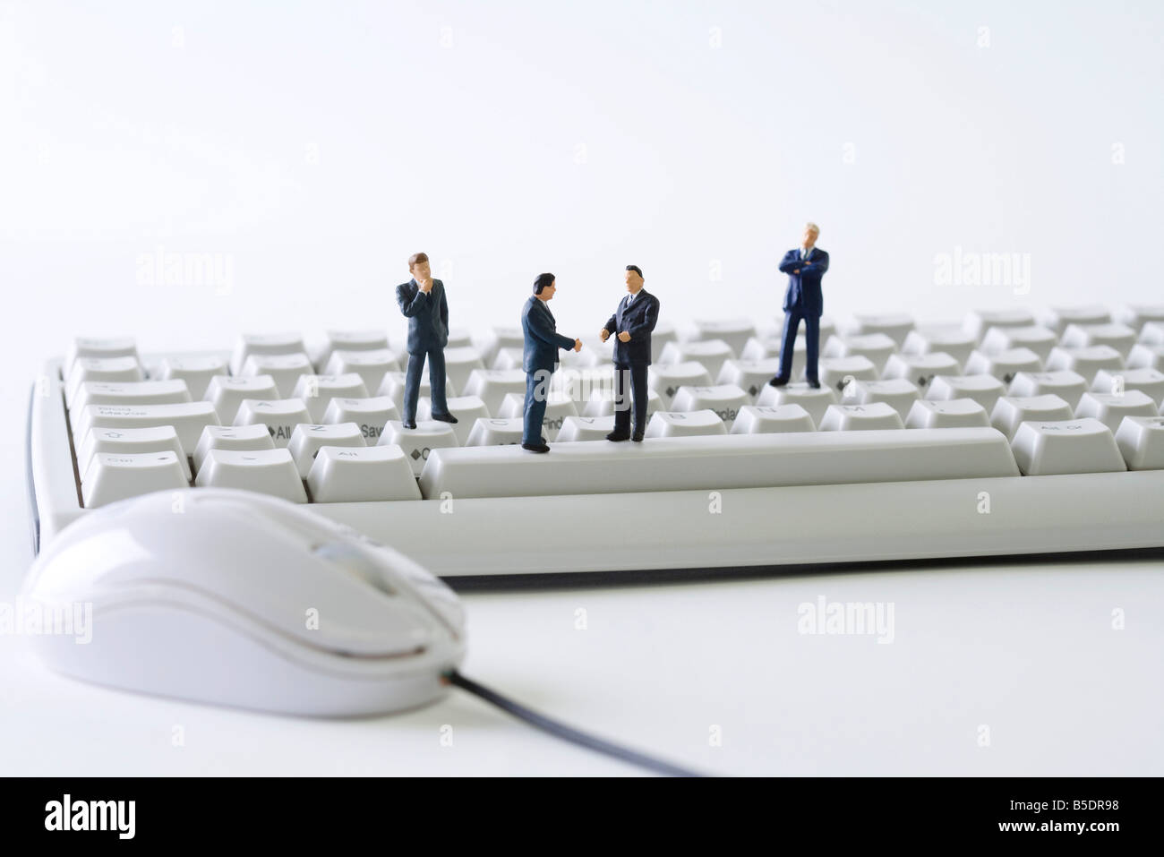 Miniature businessmen standing on computer keyboard Stock Photo