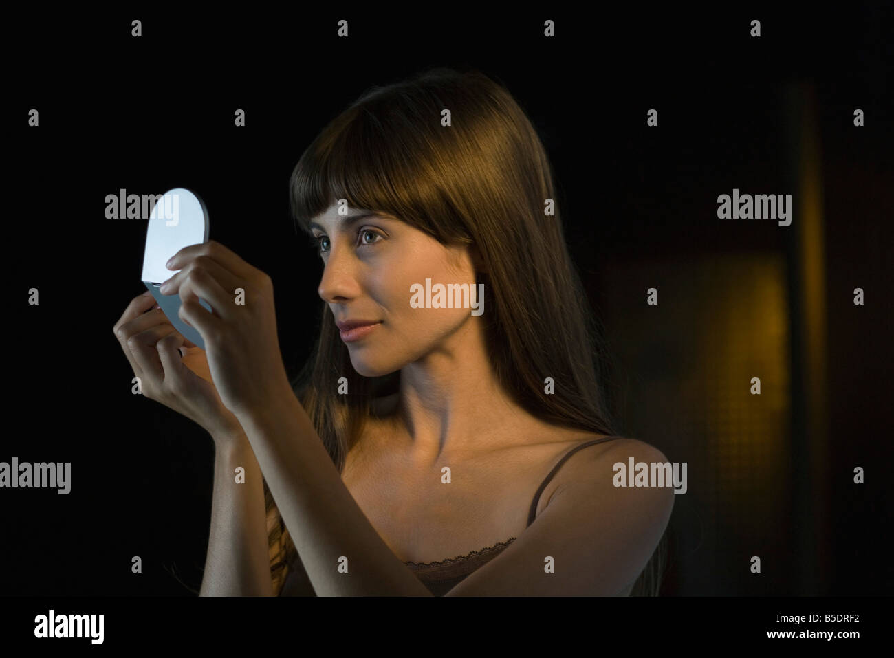 Woman looking at herself in handheld mirror Stock Photo