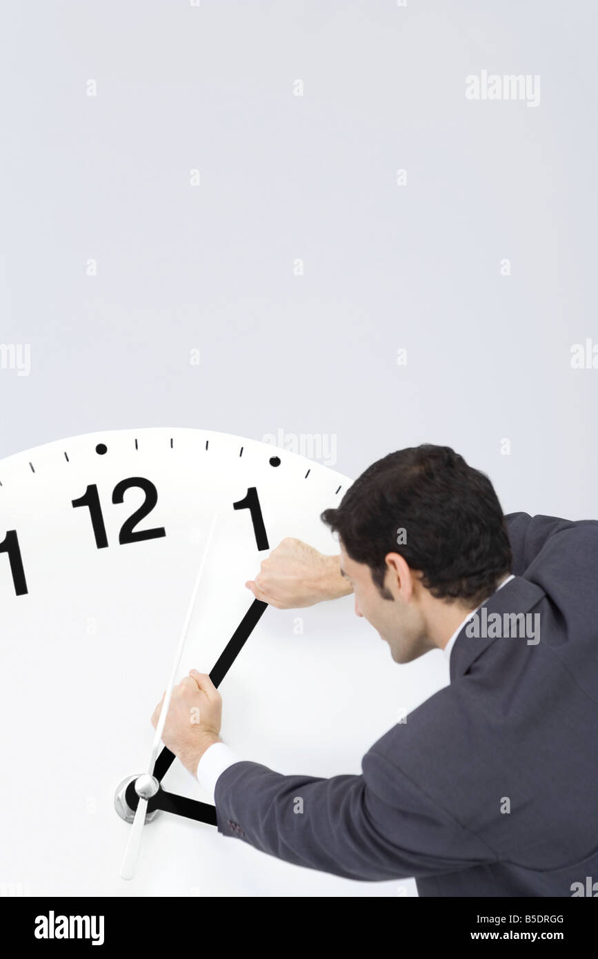 Businessman trying to turn back hands of clock Stock Photo