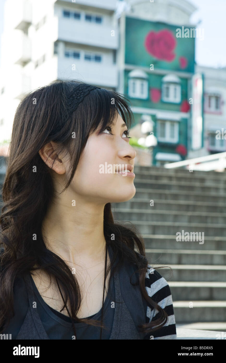 Young woman outdoors, looking up, stairs in background Stock Photo