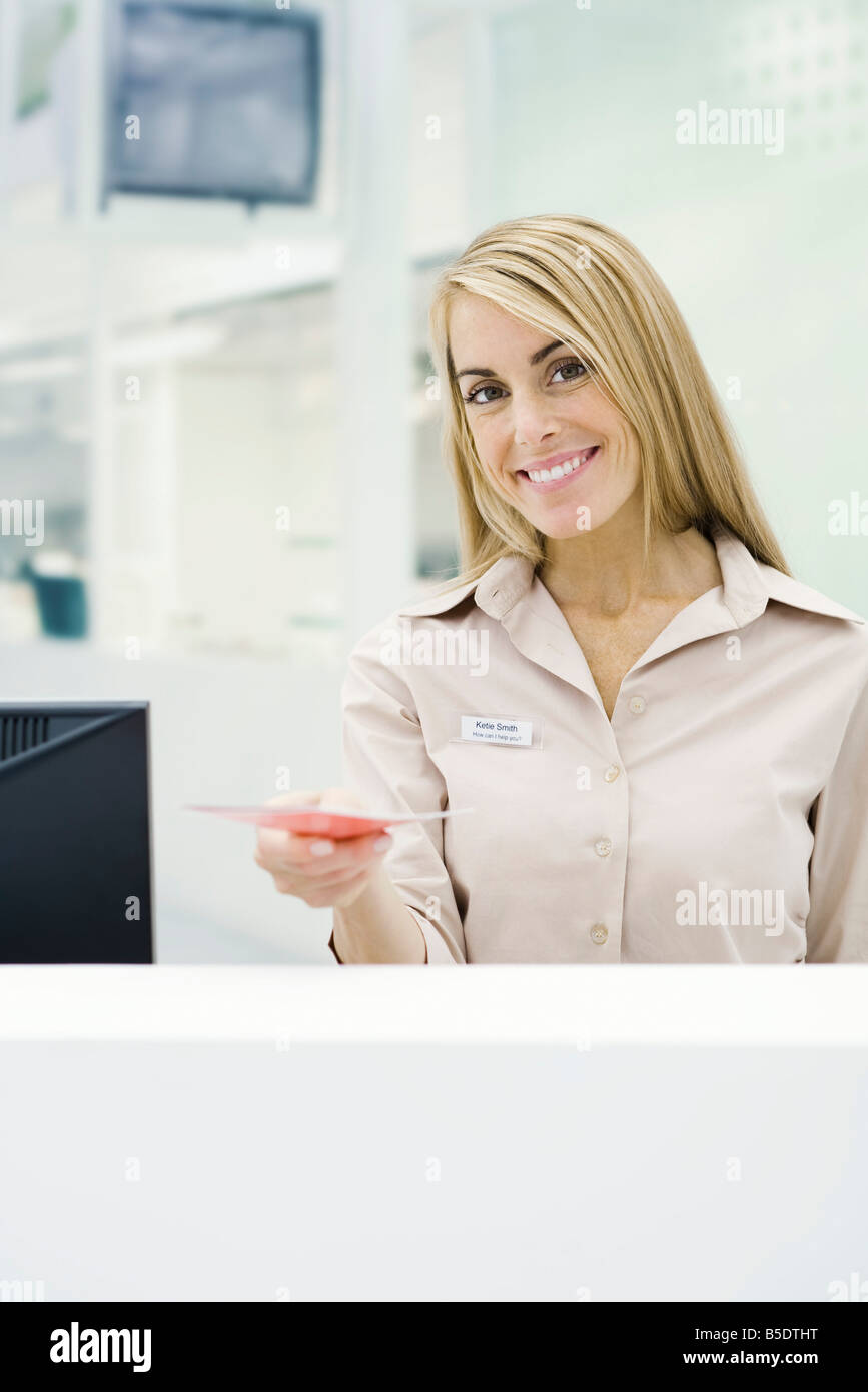 Professional woman holding out brochure, smiling at camera Stock Photo