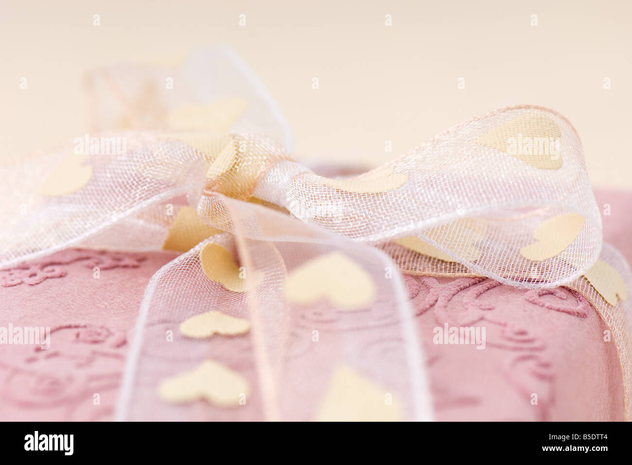 Pink gift wrapped with heart ribbon, extreme close-up Stock Photo
