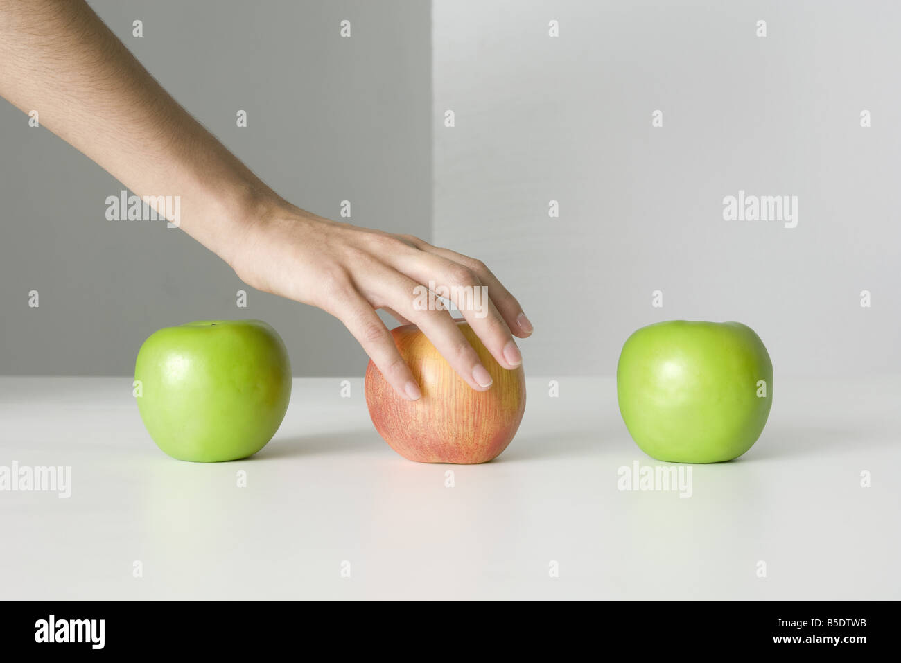 Three apples, hand selecting red apple Stock Photo