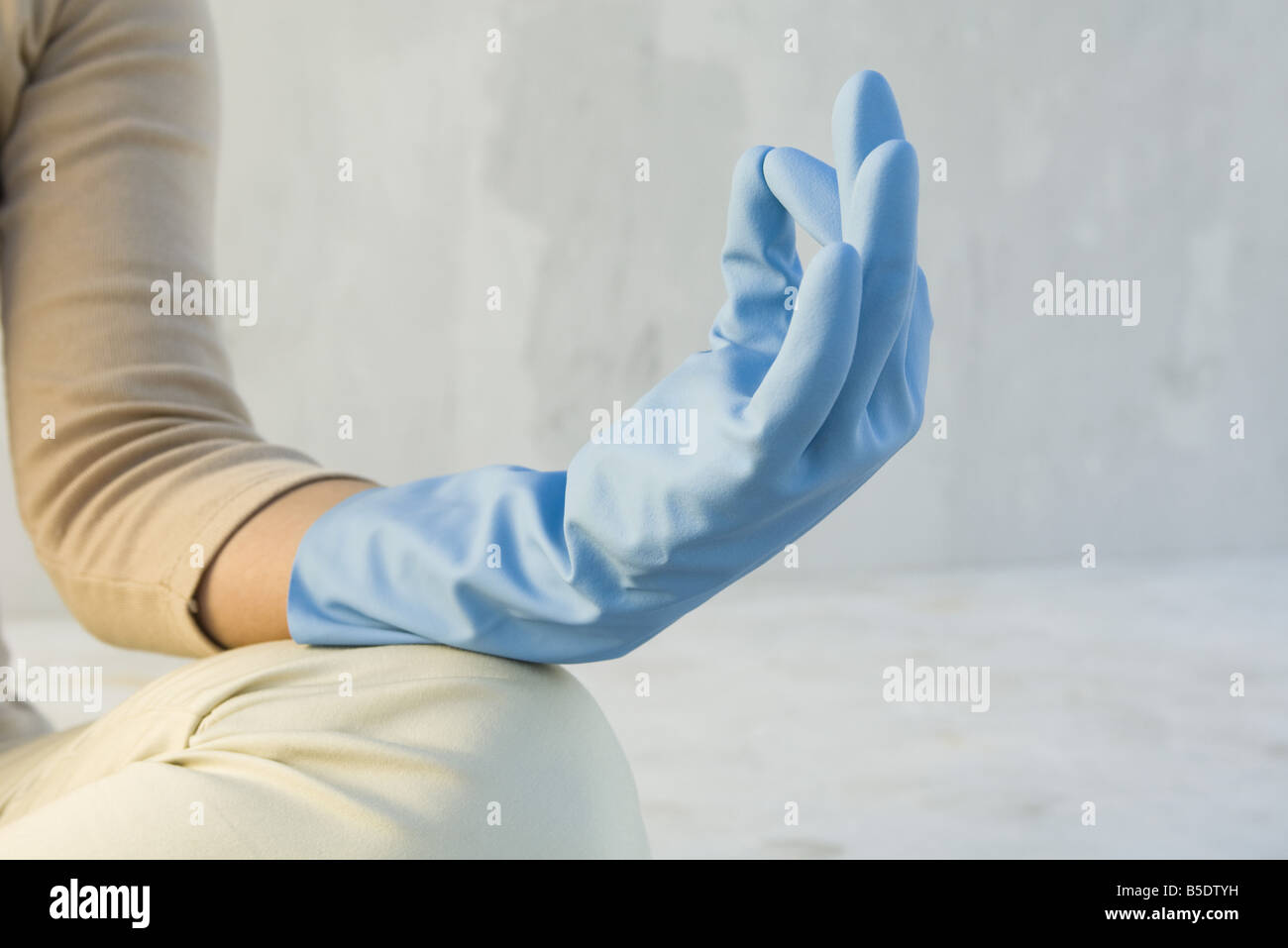 Person meditating with hand in mudra position, wearing rubber glove, cropped view Stock Photo