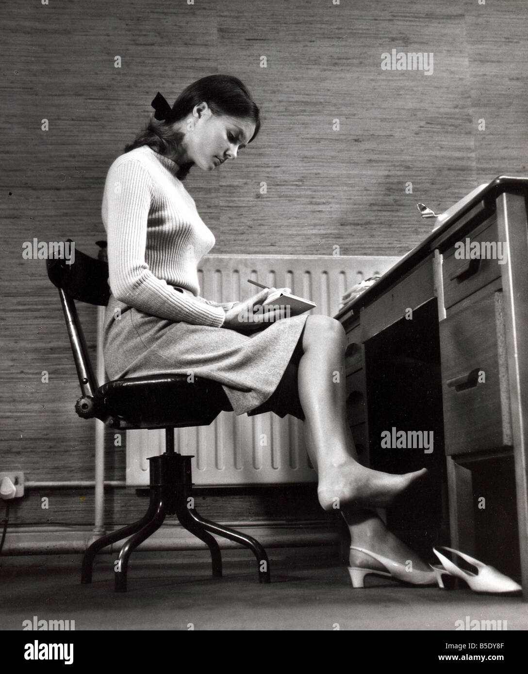 Female office worker sitting taking notes Writing barefoot taking shoe
