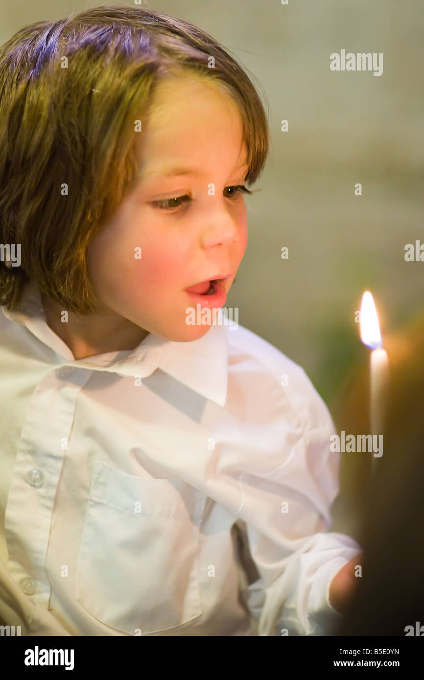 Young boy blowing out candle, at baptism ceremony Stock Photo Alamy