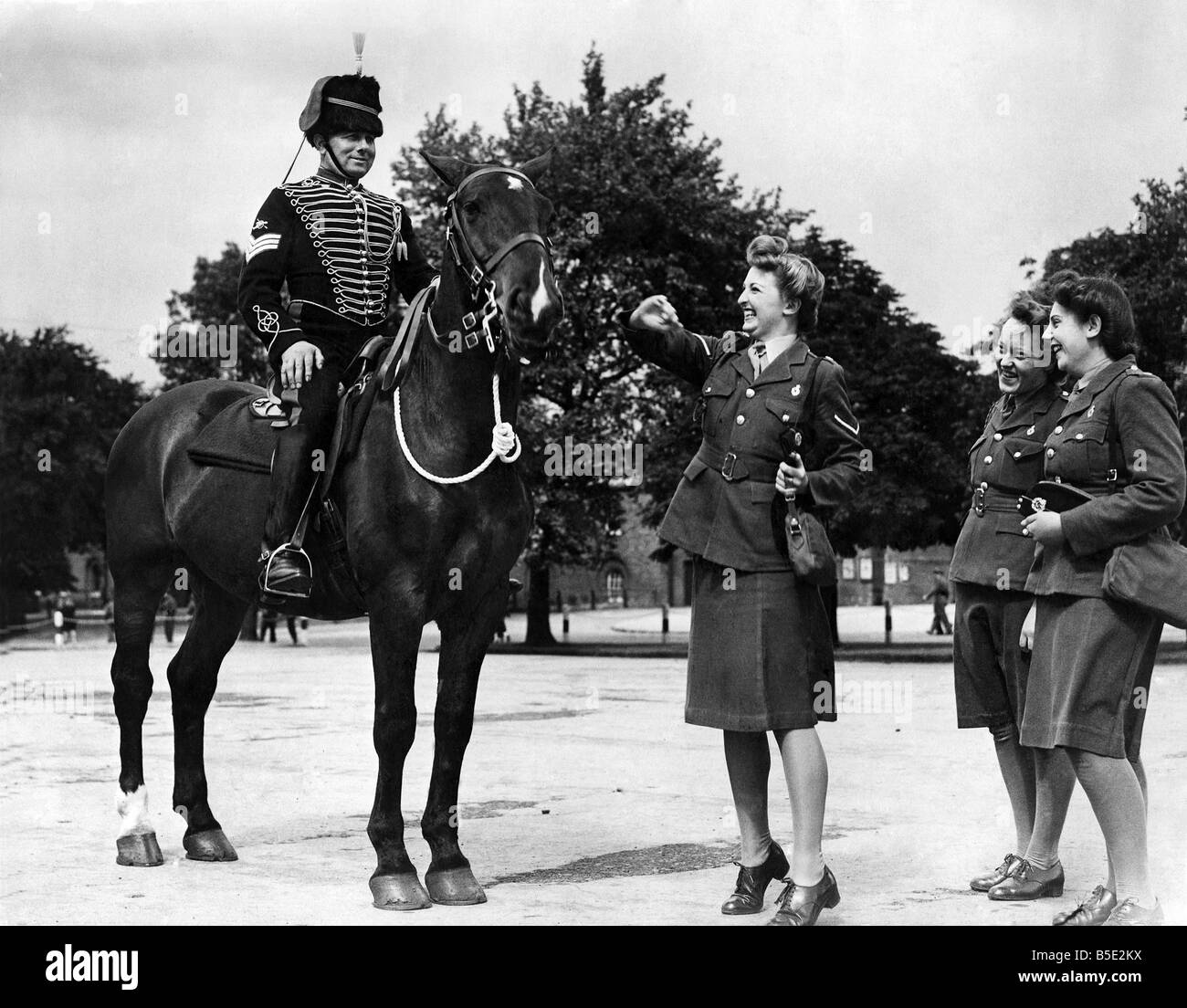 The old and the new at Woolchurch Royal Artillery Depot ;Sheila Ward of Purley, Surrey admires the old time horse of the artilery man. Mounted is Sgt. Arthur Parmented of Pitsea, Essex. ;May 1945 Stock Photo