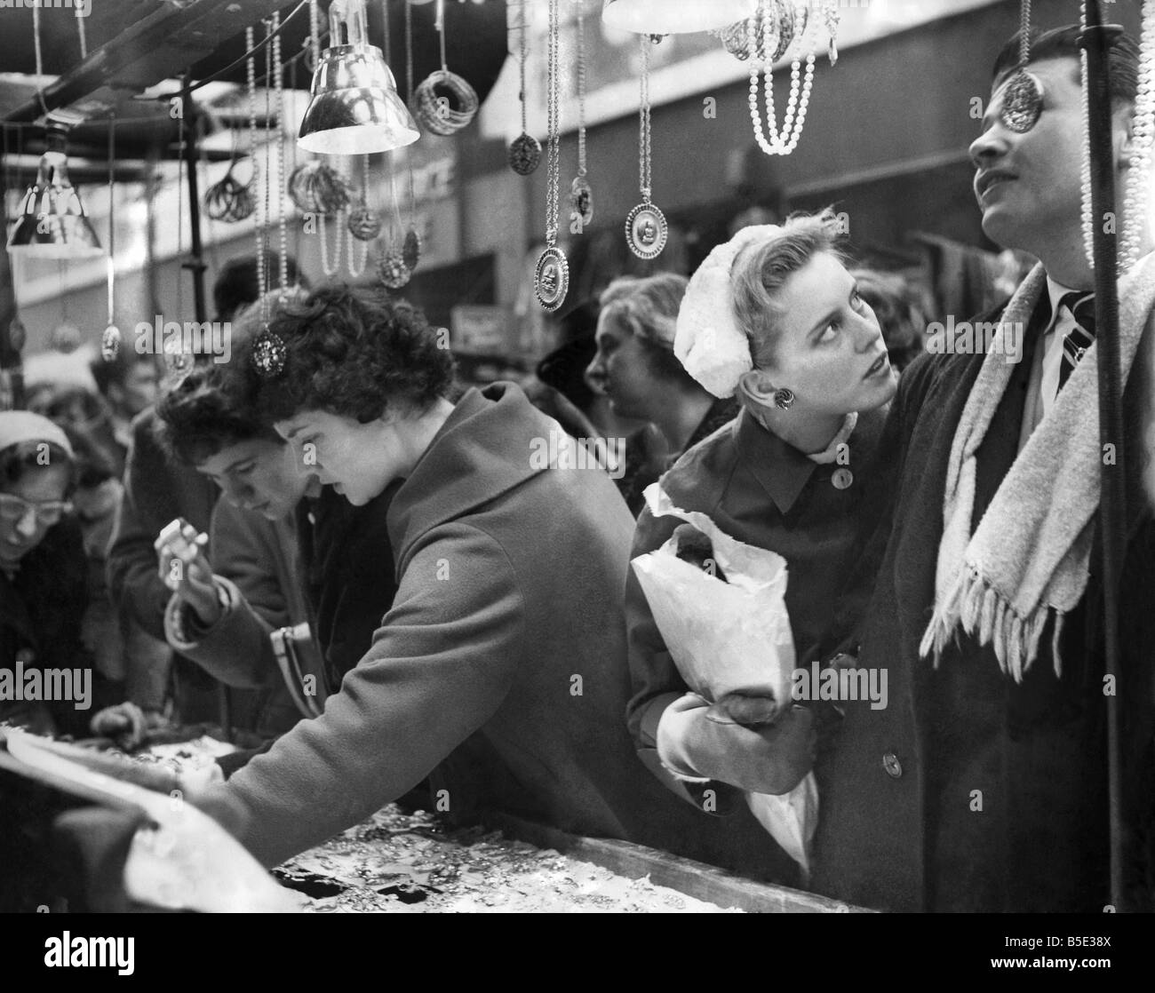 Christmas shoppers in Petticoat Lane, some carrying children others a parcel or a two. Although it was hard work to press through the crowds, it was generally thought by stall-holders and tradesmen that it was a poor Christmas Sunday in Petticoat Lane. ;December 1958 Stock Photo
