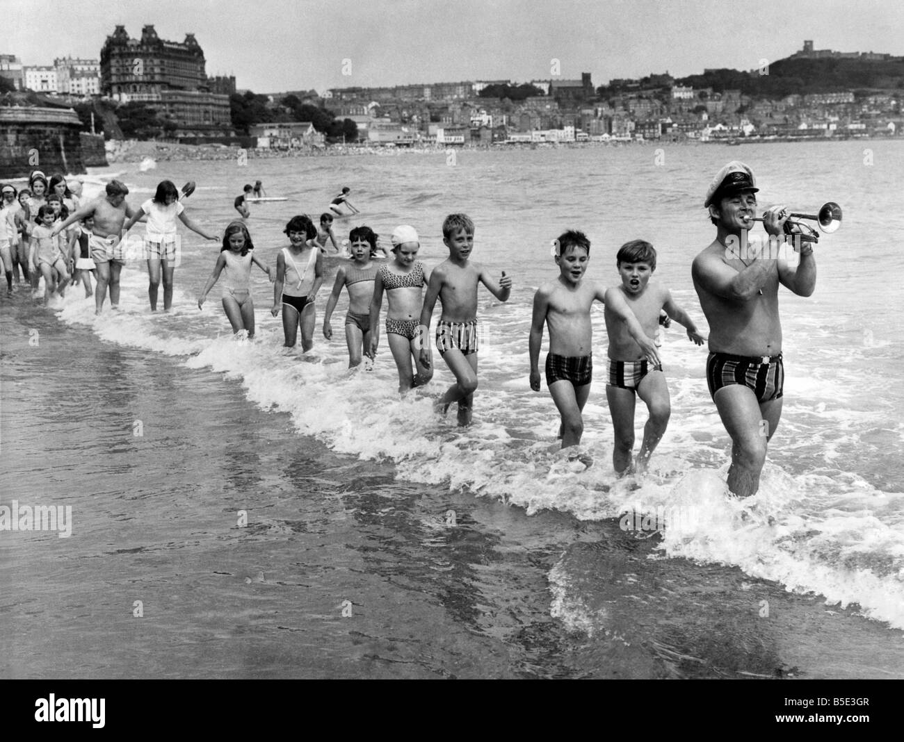 He's the Pied Piper who leads children away from the dangers that menace them at the seaside. Far from being out for revenge, like the fairy story character Cheerful Charlie Pearson, leading the line of children in the picture, is known to parents as the Safety First Swinger of Scarborough, Yorkshire. ;August 1970 Stock Photo