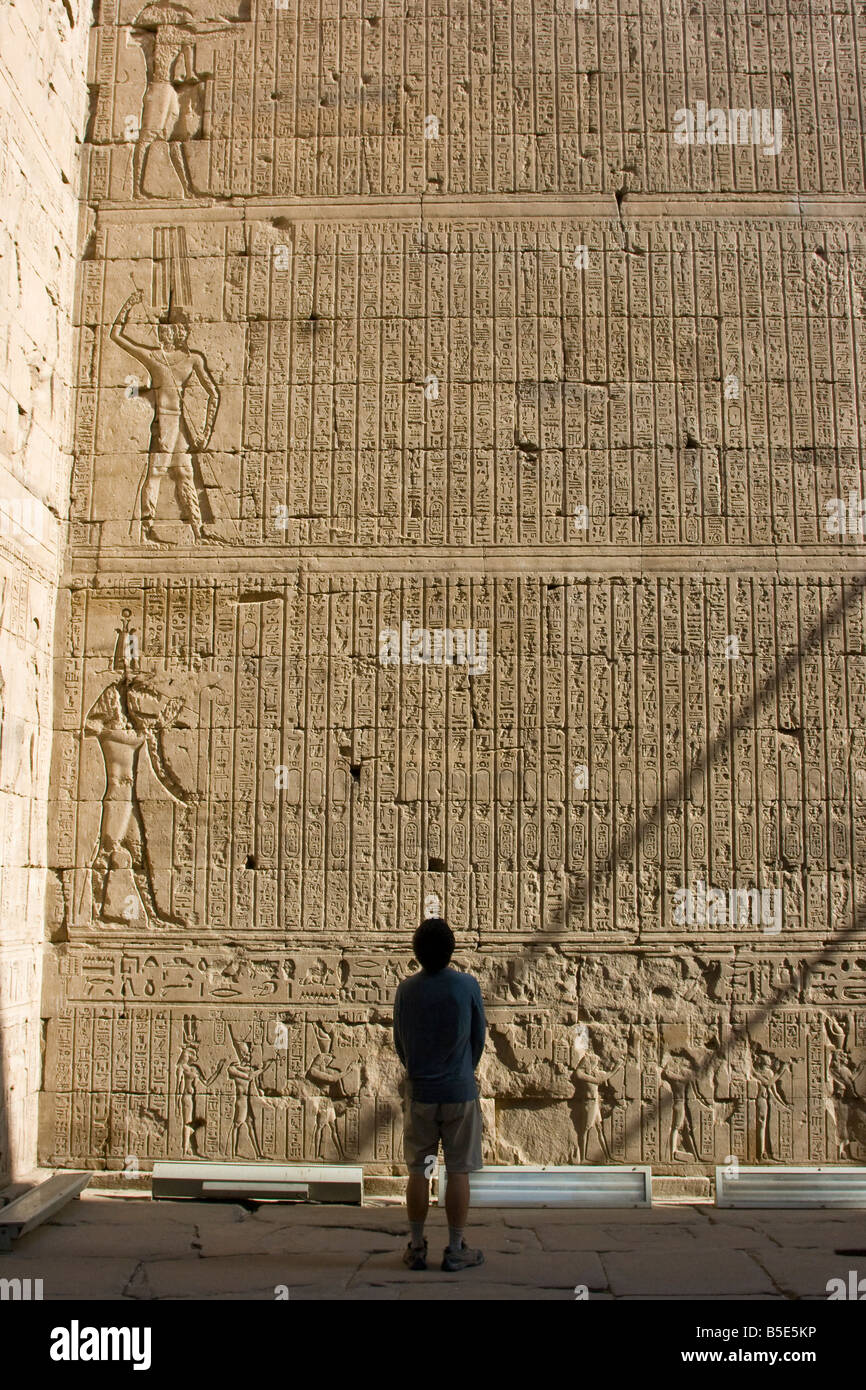Tourist Looking at a Wall of Hieroglyphs at the Temple of Horus in Edfu Egypt Stock Photo