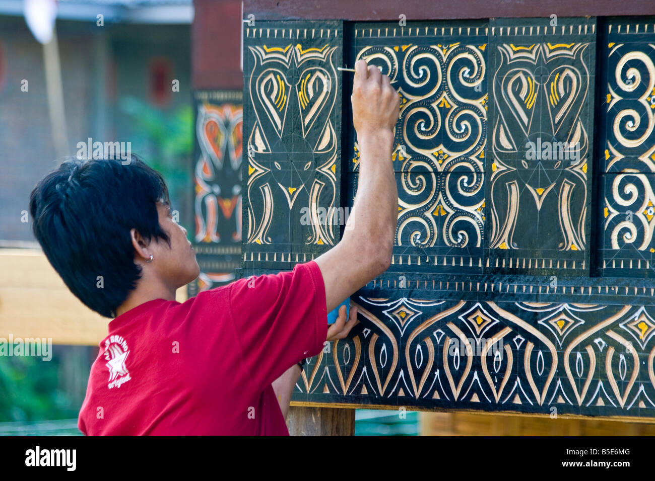Young Man Painting a Traditional Tongkonan House in Tana Toraja on Sulawesi in Indonesia Stock Photo