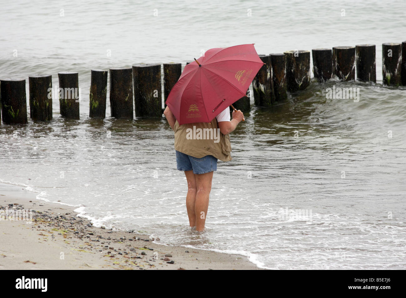 A man with an umbrella standing in the water, Heiligendamm, Germany Stock Photo