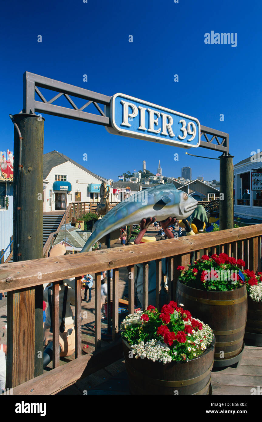 Sign for Pier 39 Fisherman apos s Wharf with Coit Tower and Transamerica Pyramid on city skyline in the background San Stock Photo