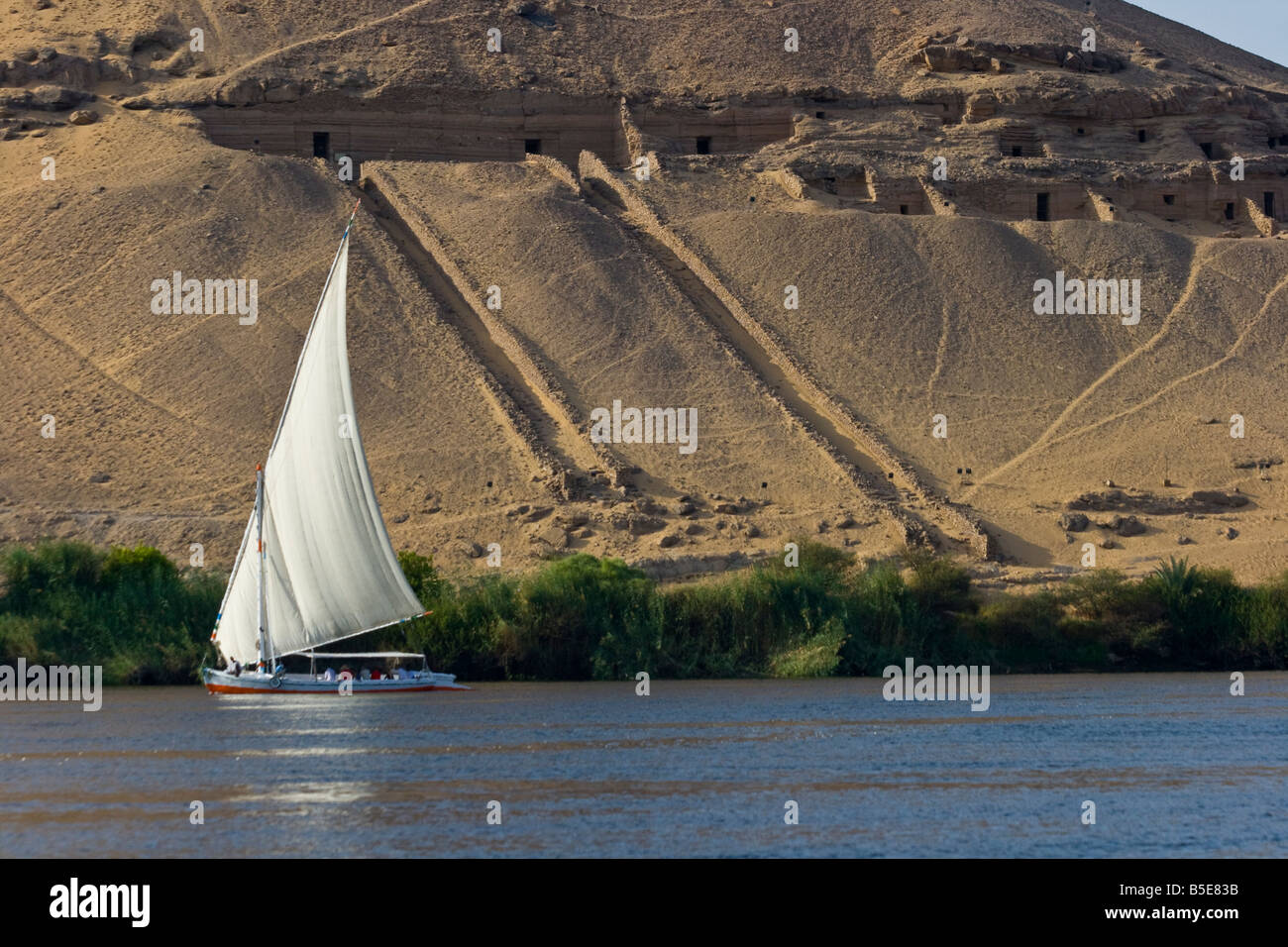 Tombs of the Nobles and Felucca Sailboat on the Nile River in Aswan Egypt Stock Photo