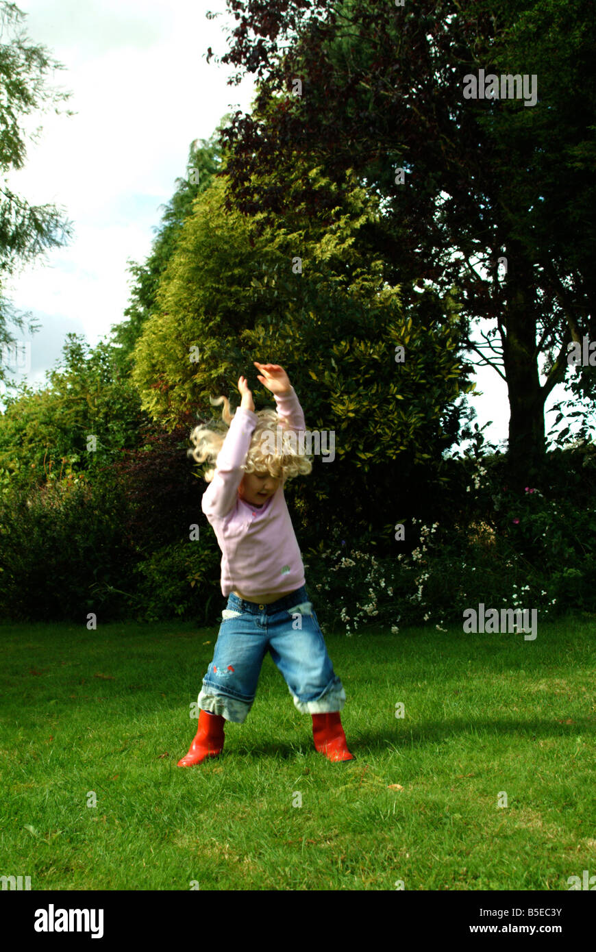 Little girl jumping in the air in red wellington boots Stock Photo - Alamy