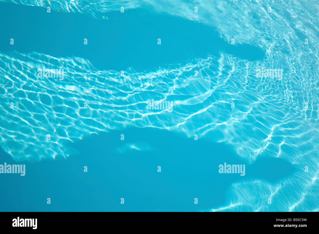 patterns of sunlight rippling on a swimming pool water surface with two ...