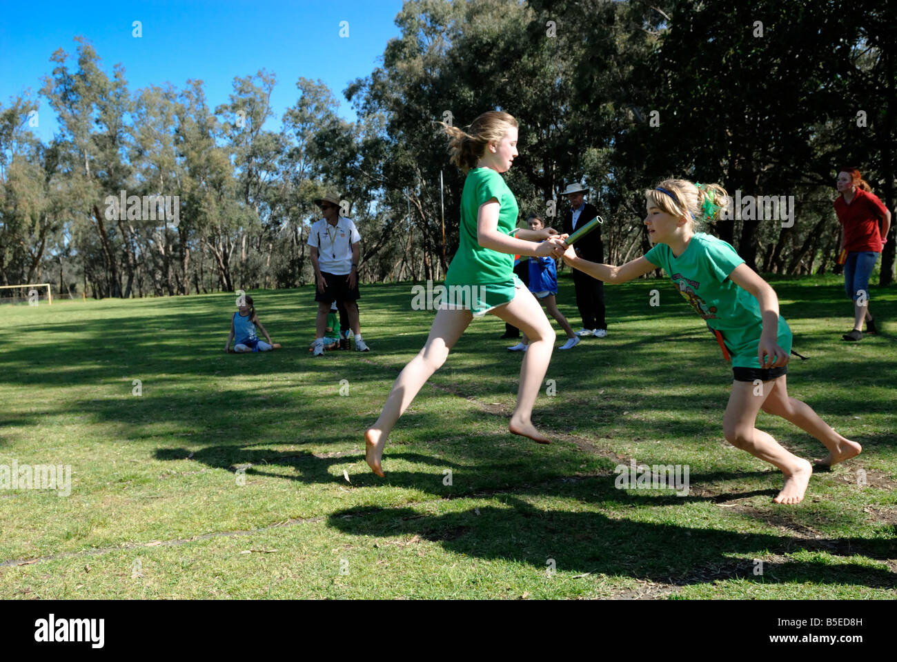 Handover of baton in relay race. Primary school sports day in Australia