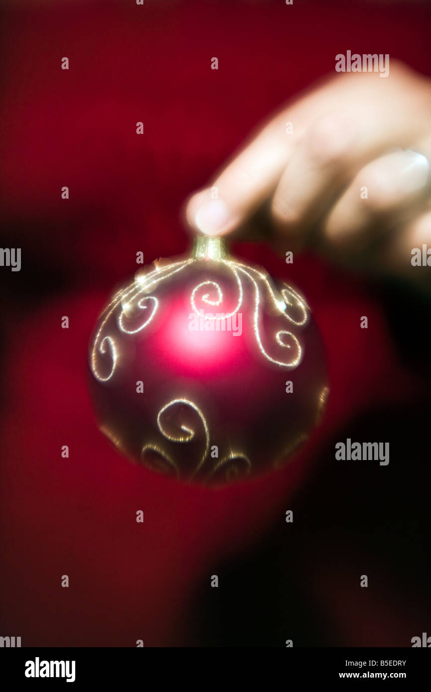 woman holding a red and gold Christmas glass ornament Stock Photo