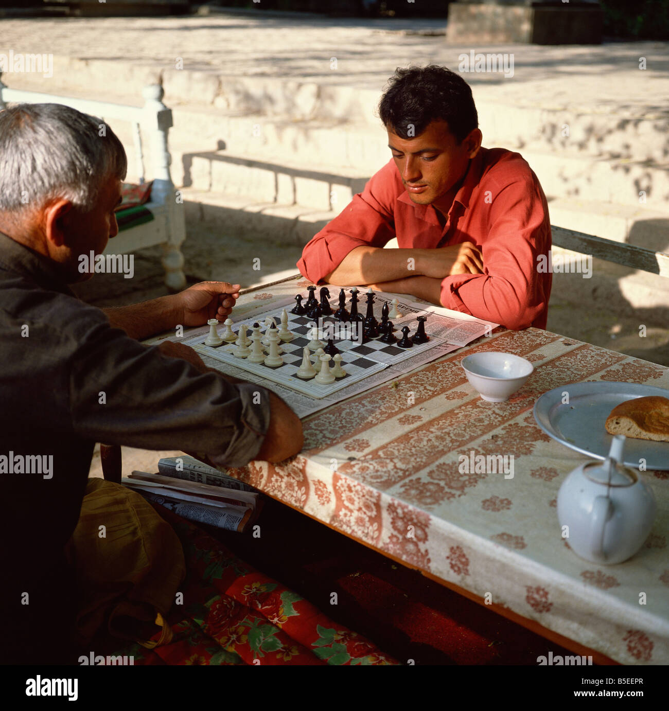 Uzbek men playing chess in a tea house garden, Bukhara, Uzbekistan, Central Asia Stock Photo