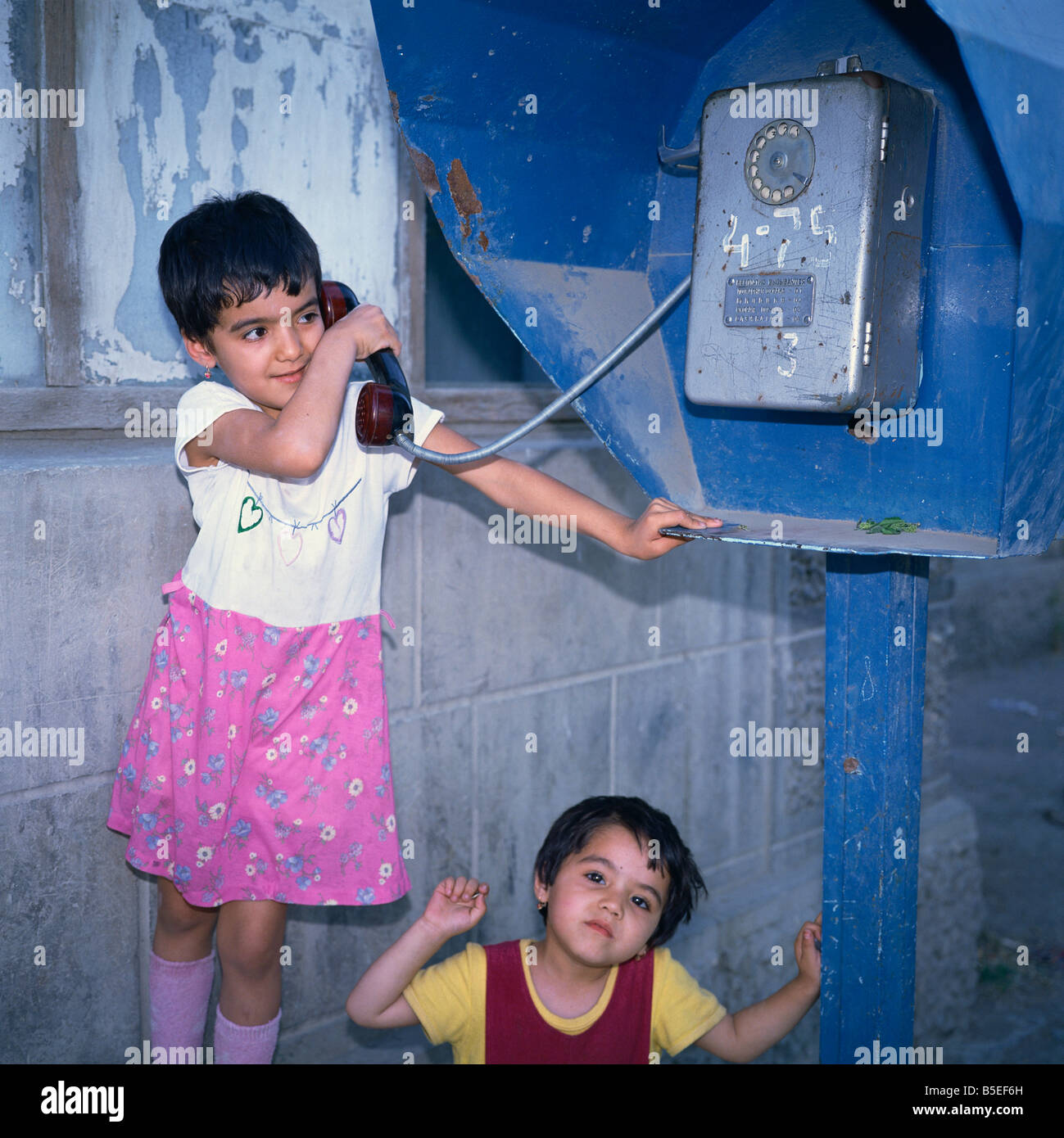 Two small Uzbek girls using the public telephone in Bukhara Uzbekistan Central Asia Stock Photo