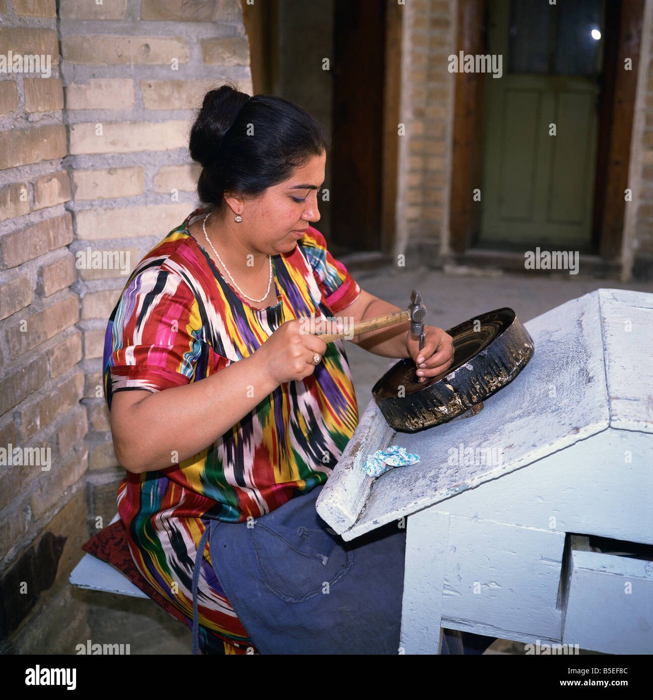 Uzbek woman engraving copper in Bukhara Uzbekistan Central Asia Stock Photo