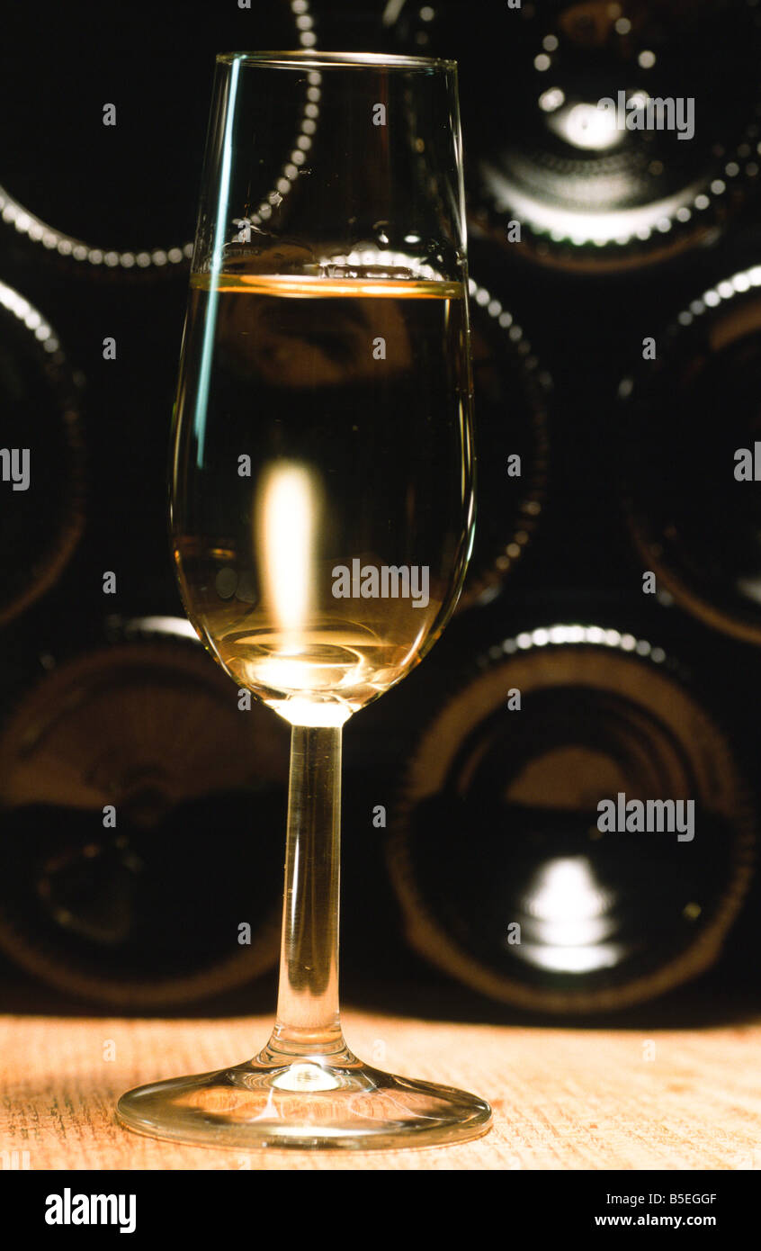 a glas of white wine in front of bottles Stock Photo