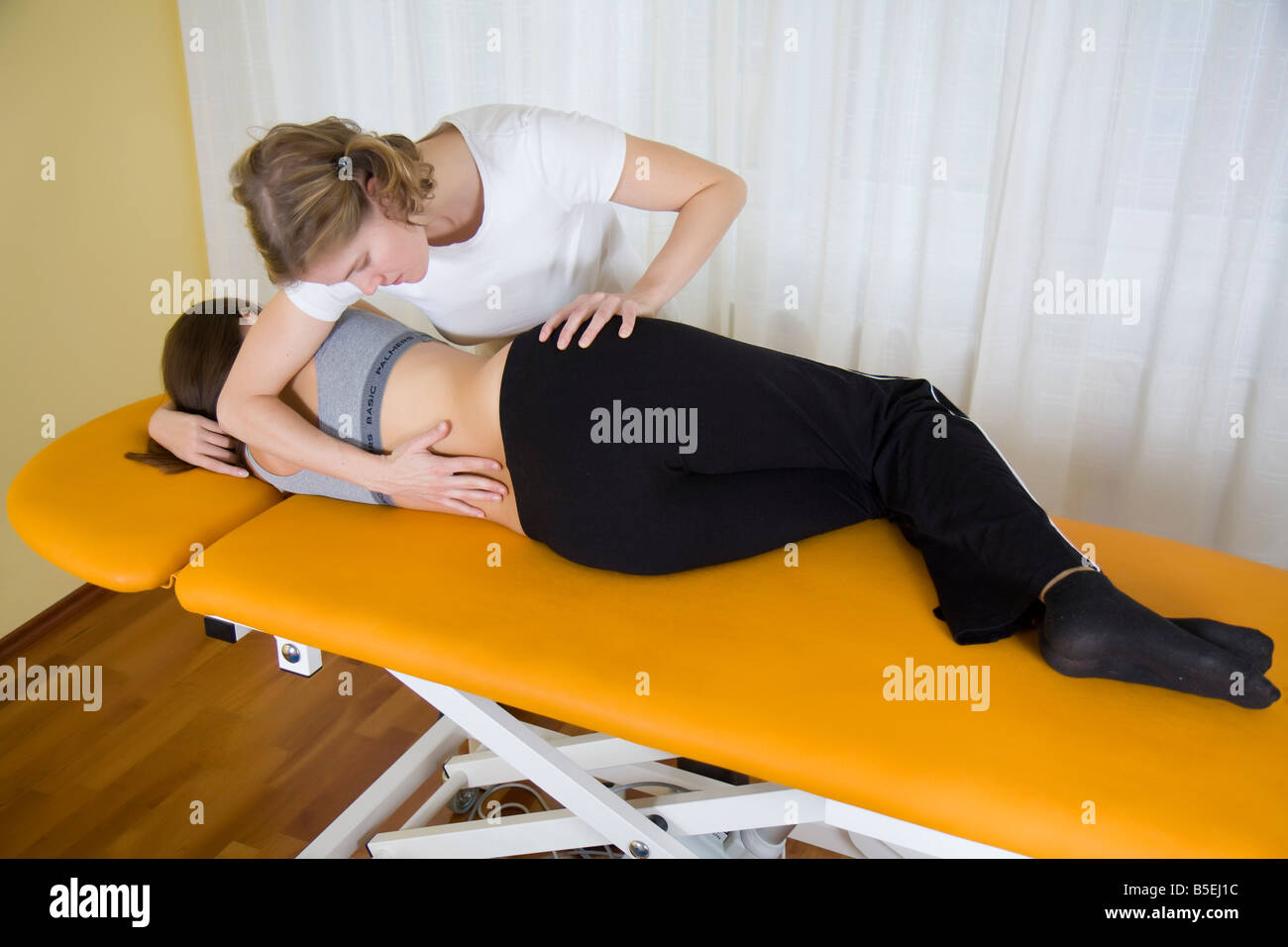 physio therapy therapist relaxes tensions of back muscles Stock Photo