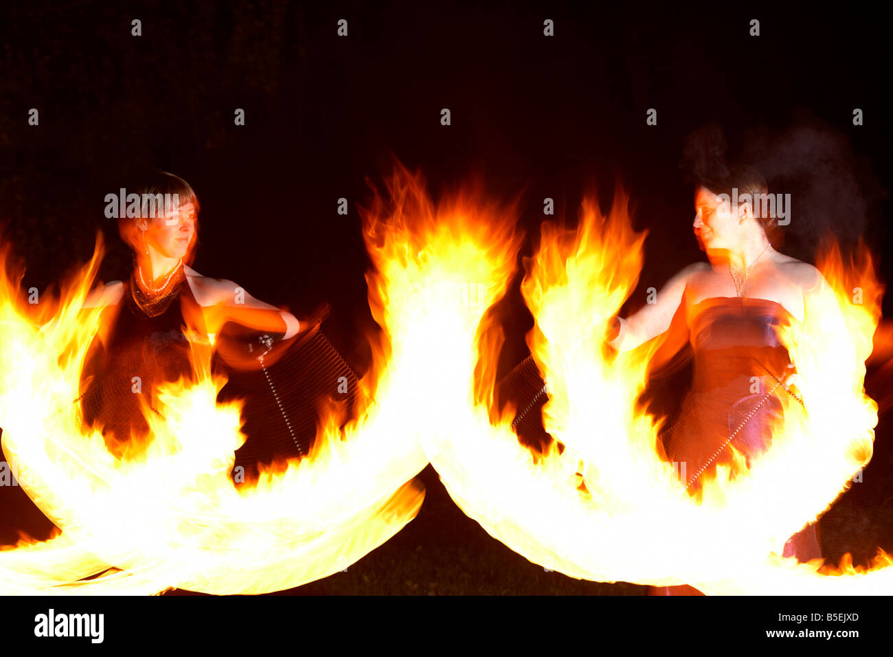firepoise two female fire dancers dance with poi flames during
