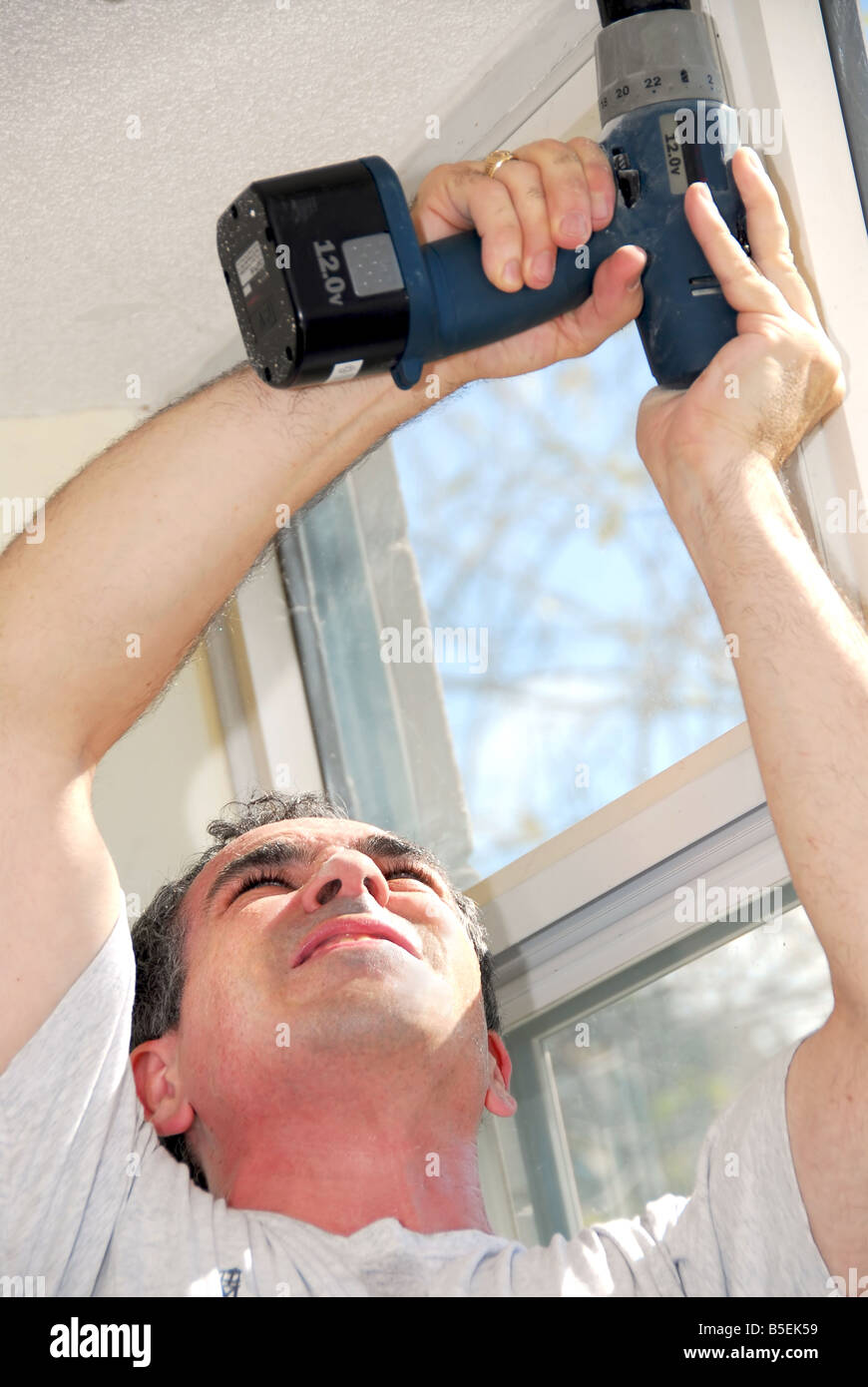Man drilling a hole in a ceiling Stock Photo