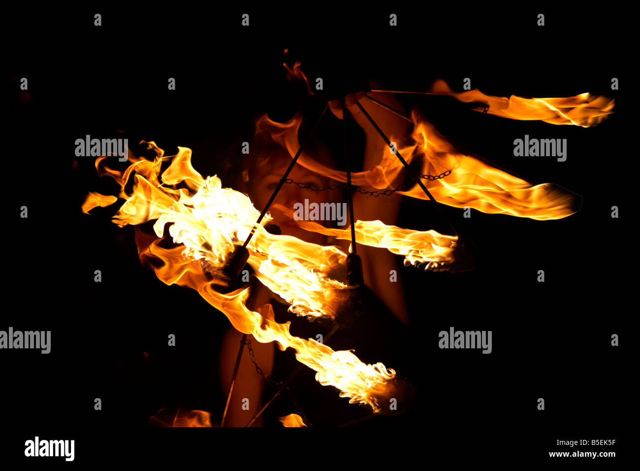 firepoise female fire dance performance artist holding fire fans at