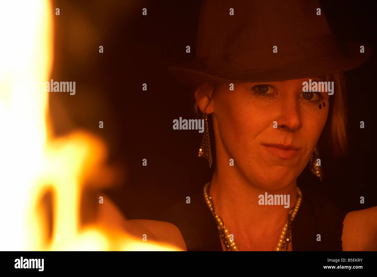 firepoise female fire dance performance artist wearing hat holding fire