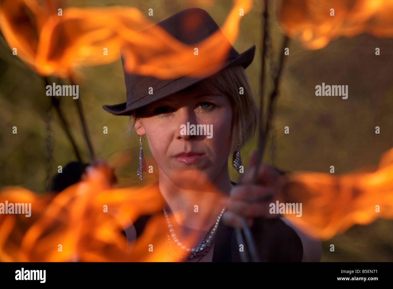 firepoise female fire dance performance artist wearing hat holding fire fans Stock Photo
