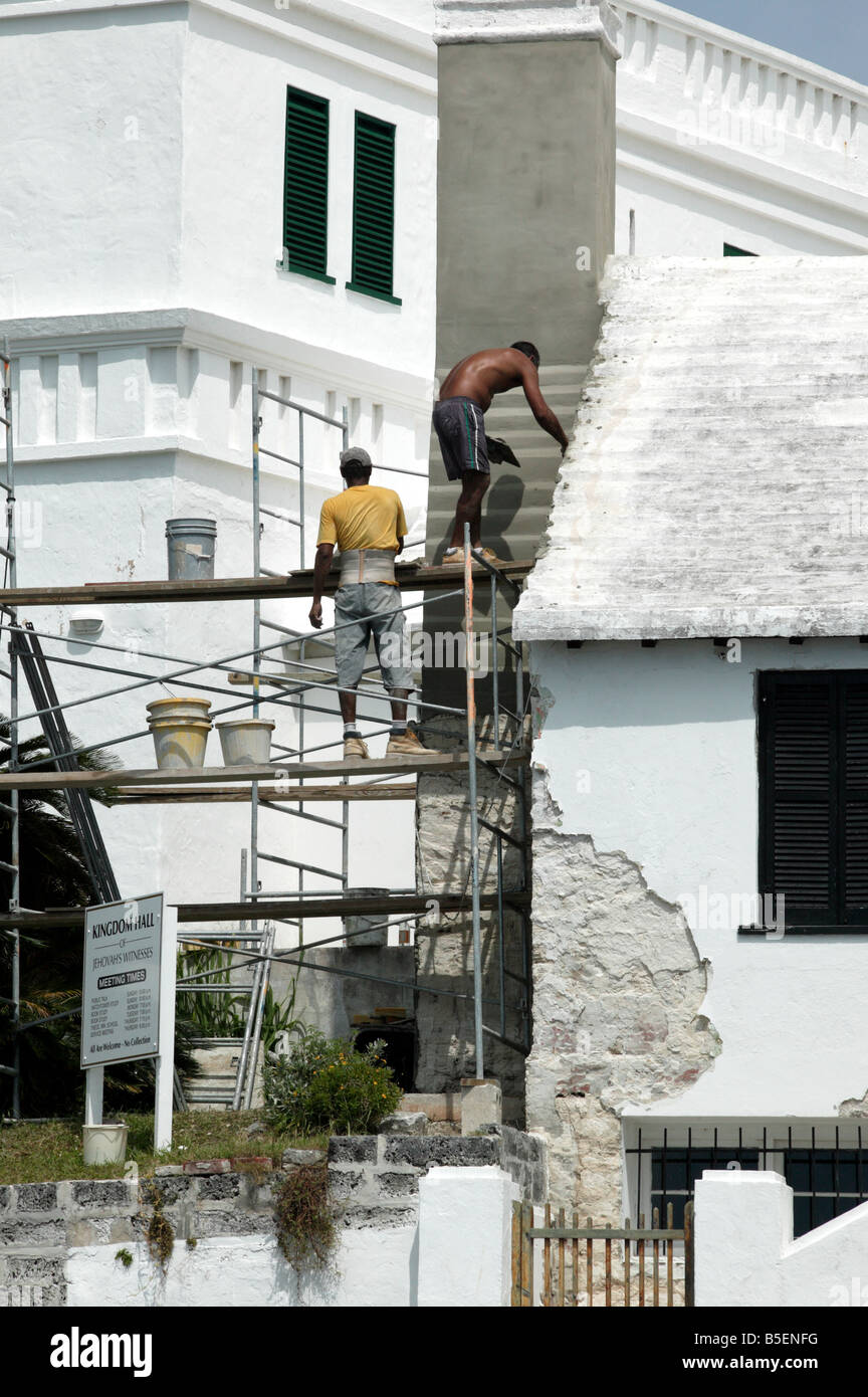 Shot of two workmen doing repairs to the roof and walls of a house in St George,  Bermuda Stock Photo