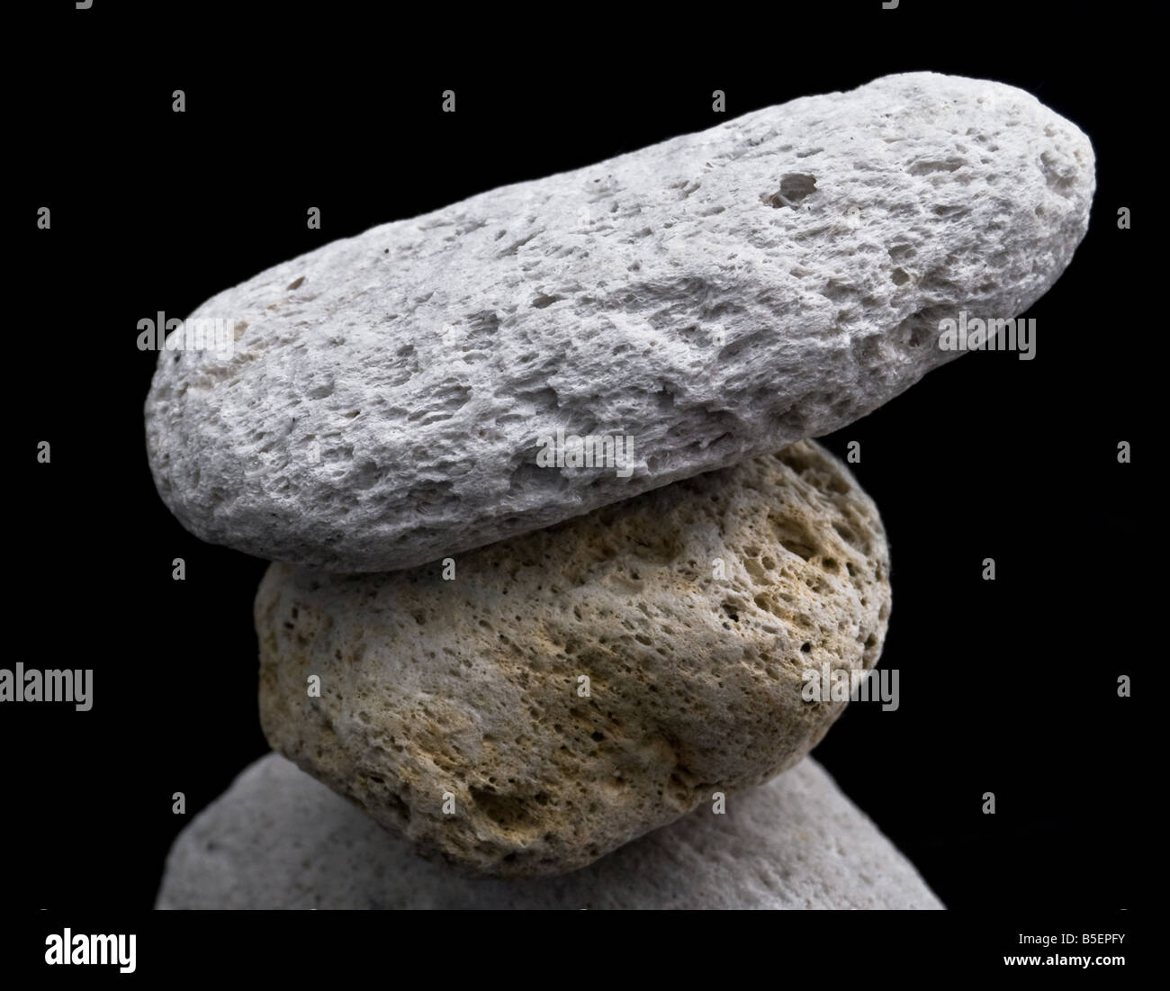 One odd color pumice stone pressed in between 2 other stones Stock Photo