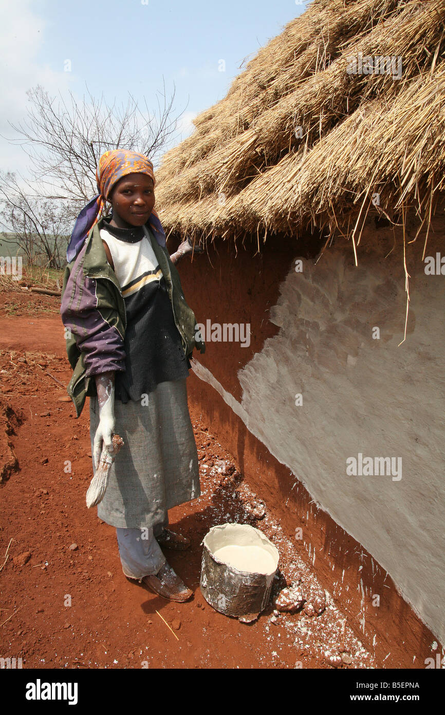 Swazi woman applying paint to her mud hut, Gege region, Swaziland, Africa Stock Photo