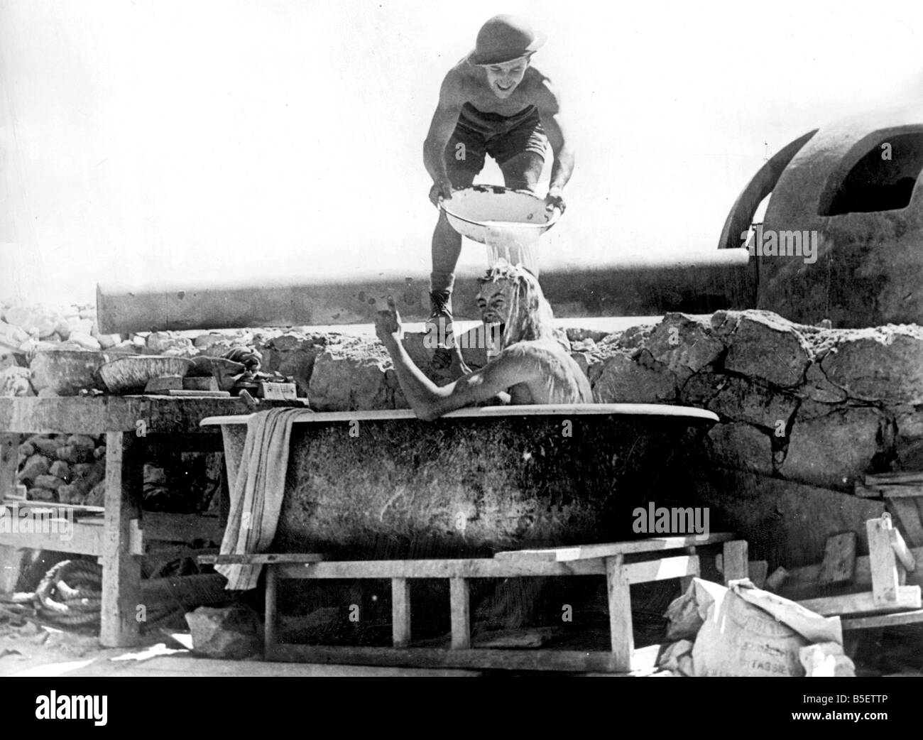 One of the crew of the coastal defence guns in Tobruk, takes a bath under the shadow of the gun, during the Allied occupation of Libya in Northern Africa;September 1941 Stock Photo