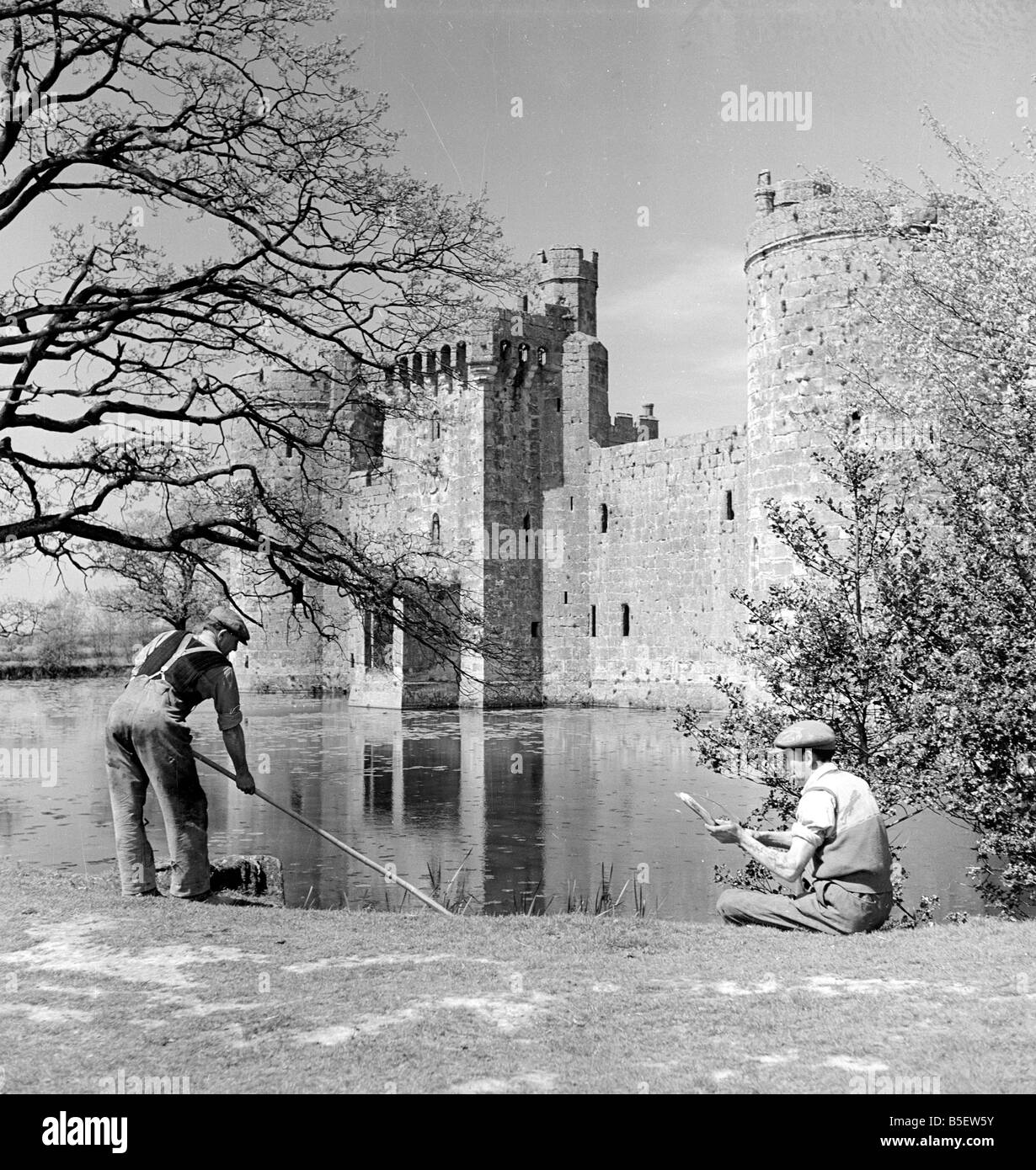 A groundkeeper cleaning the moat outside Bodiam Castle in Kent 5th May