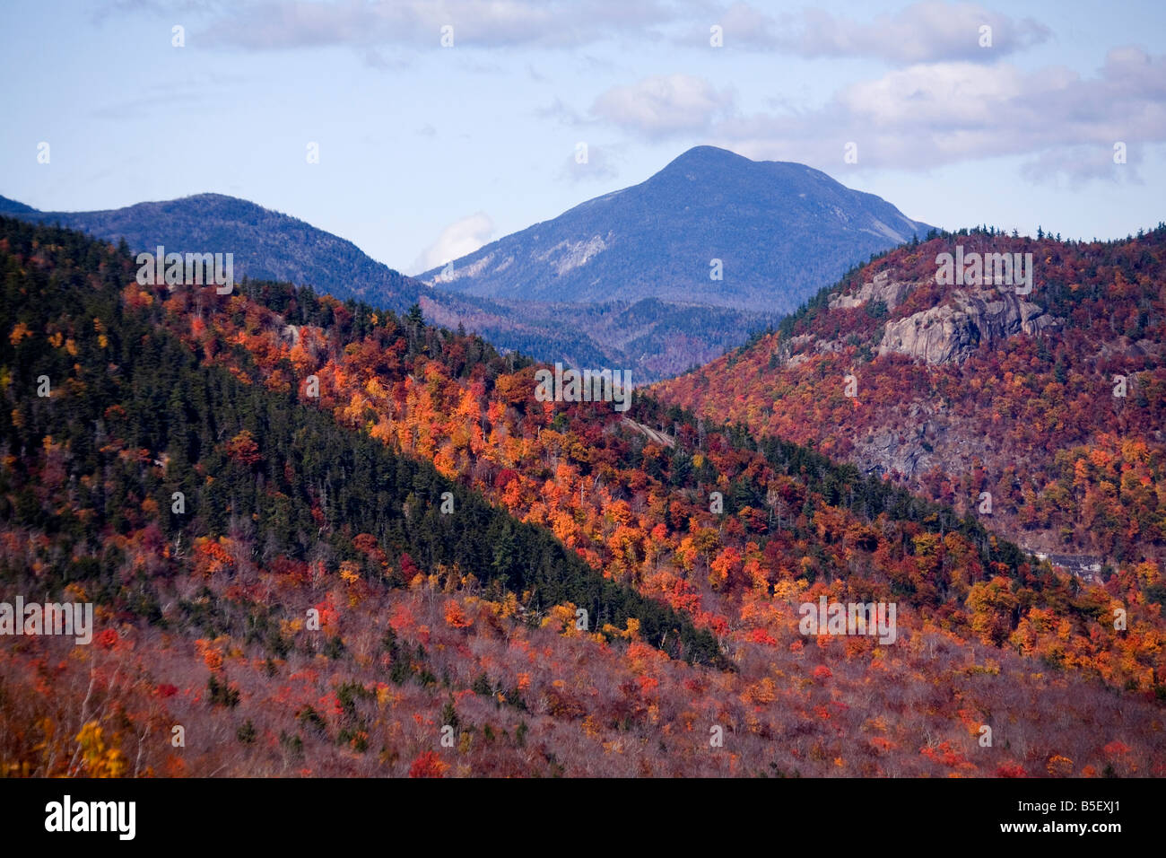 A view from the Kankamagus Highway in New Hampshire, showing trees in full autumn colors and a distant mountain. Stock Photo