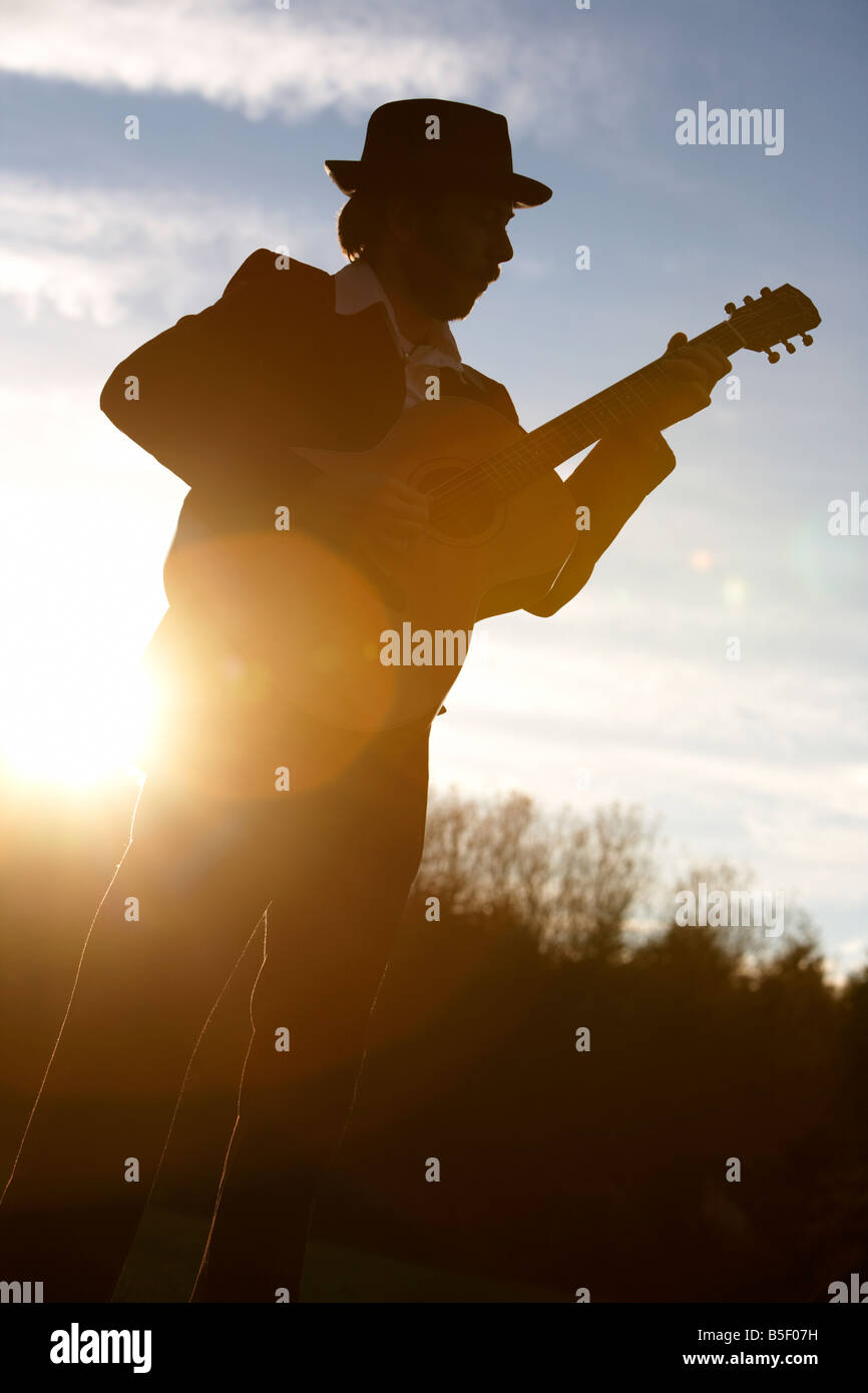 bearded 20s man playing guitar outdoors Stock Photo