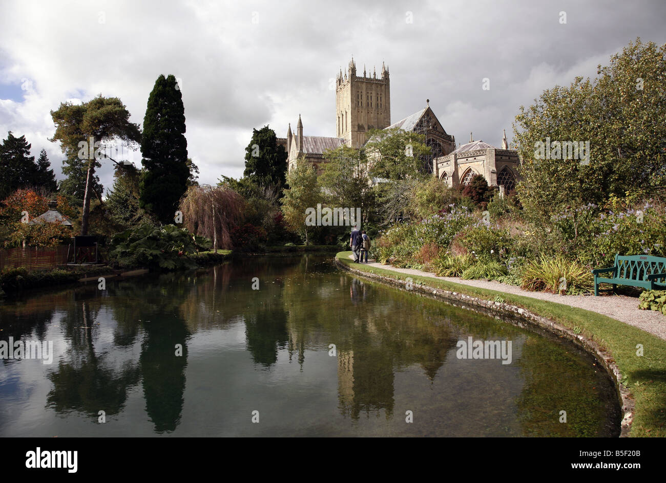 Wells Cathedral reflected in the wells, from which the city gets its name, inside the grounds of the Bishops Palace Stock Photo