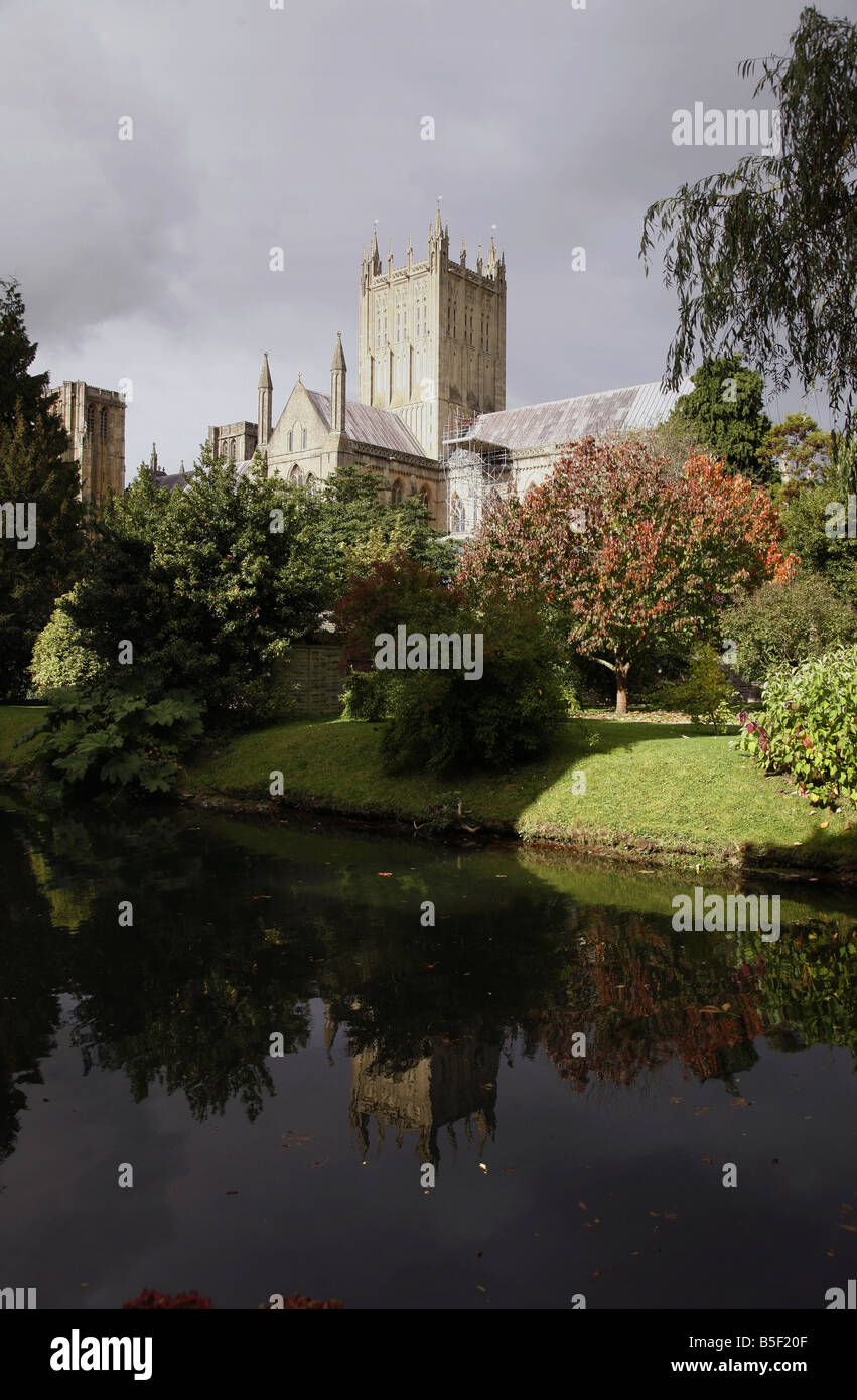 Wells Cathedral reflected in the wells, from which the city gets its name, inside the grounds of the Bishops Palace Stock Photo