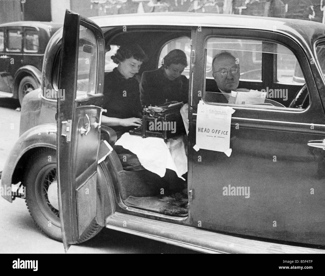 Engineering firm receives direct hit. Director of the company sits outside in his car dictating to his secretary. Apr. 21st 1941 Stock Photo