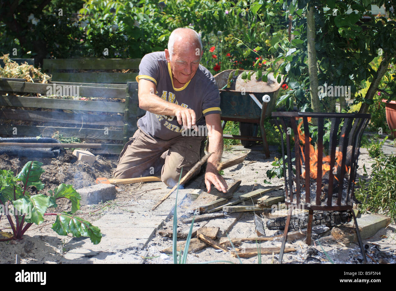 A man is throwing wood in a firebasket Stock Photo Alamy
