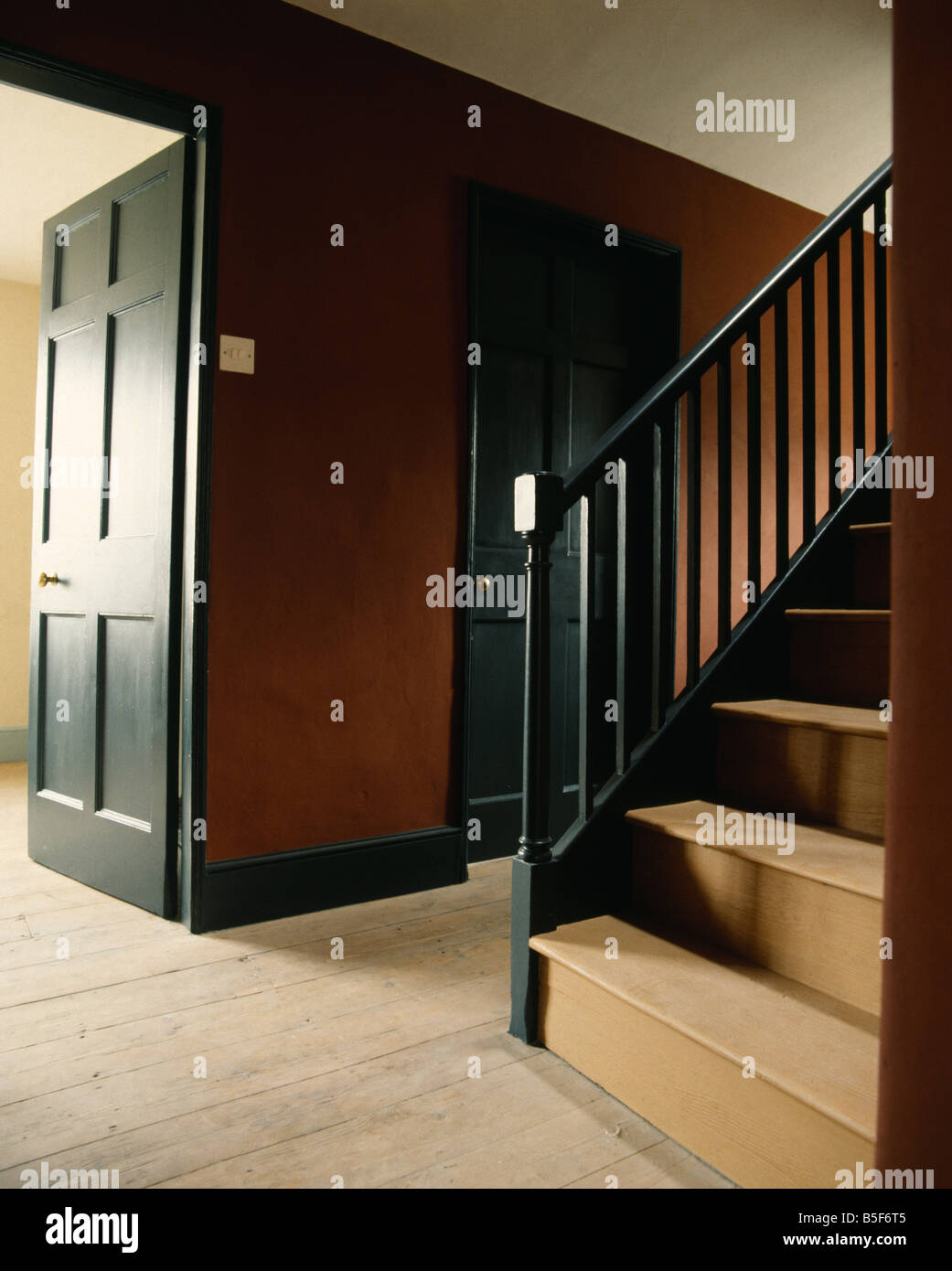 Dark green paintwork in traditional hall with bare floorboards and