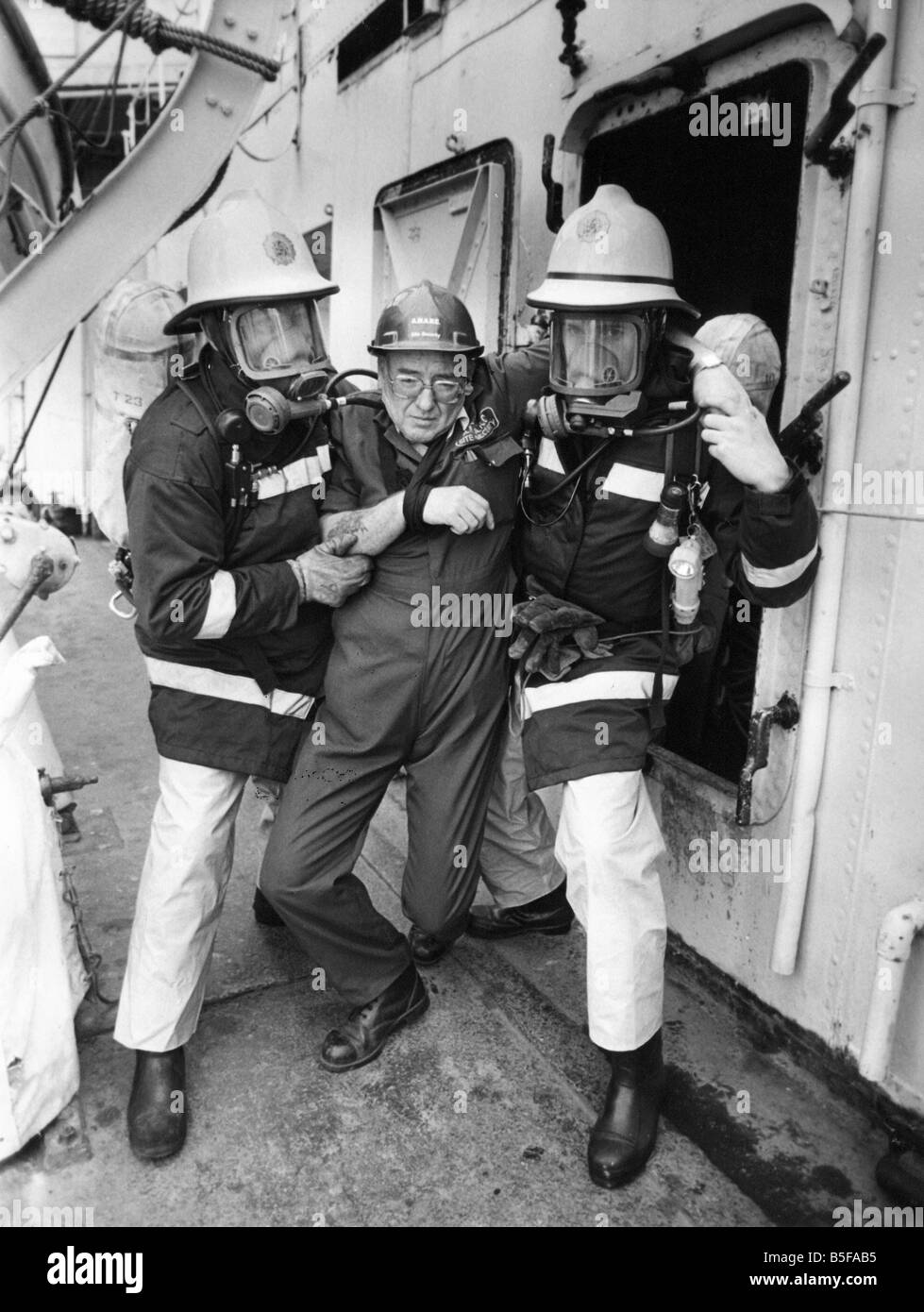 Firefighters taking part in a training exercise aboard former destroyer HMS Cavalier carry a victim from below decks Stock Photo